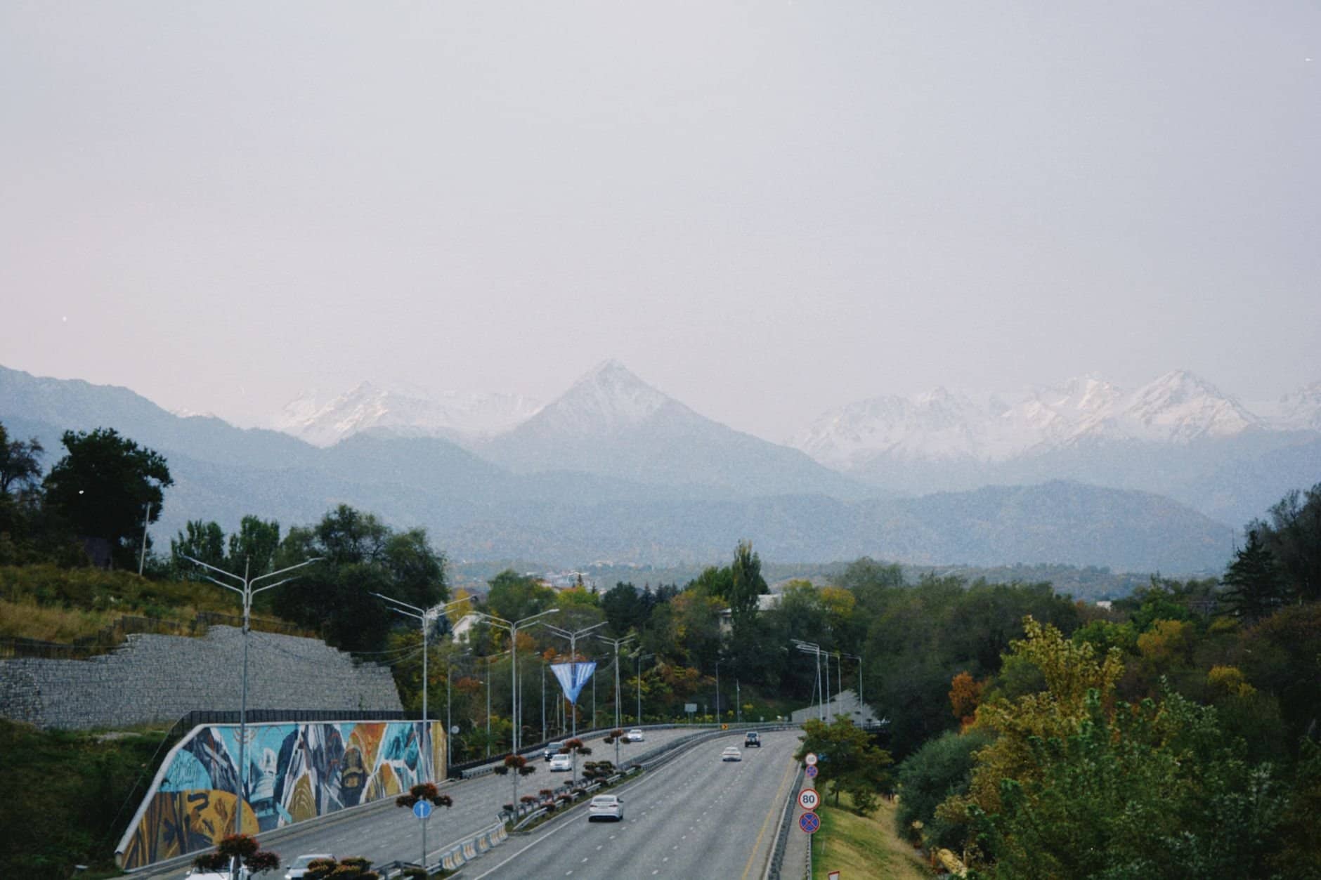 A picturesque road in Almaty, Kazakhstan, with stunning mountain backdrop and vibrant autumn foliage.