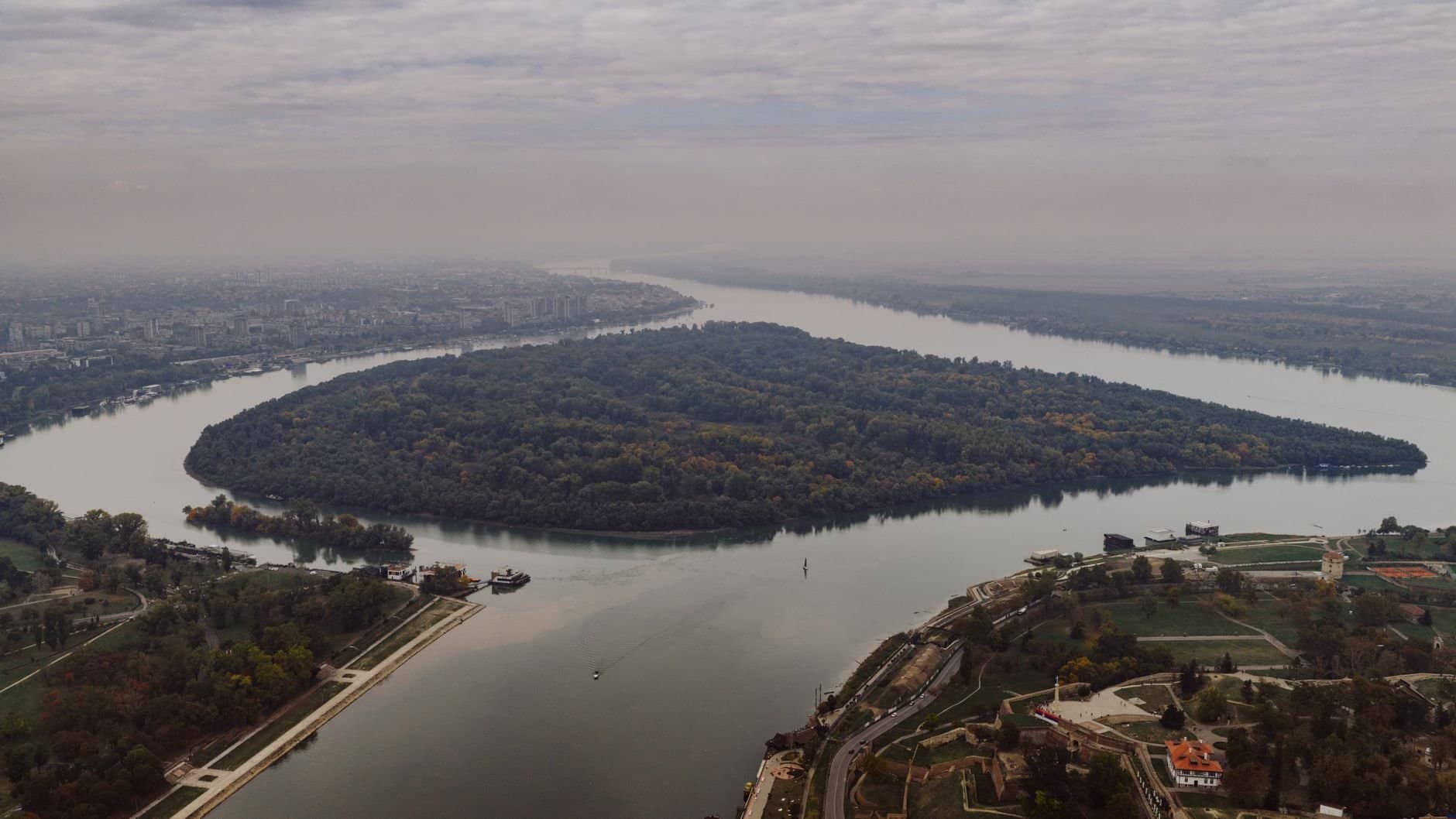 Stunning aerial shot of the river bend in Belgrade, Serbia, showcasing lush greenery and cityscape.