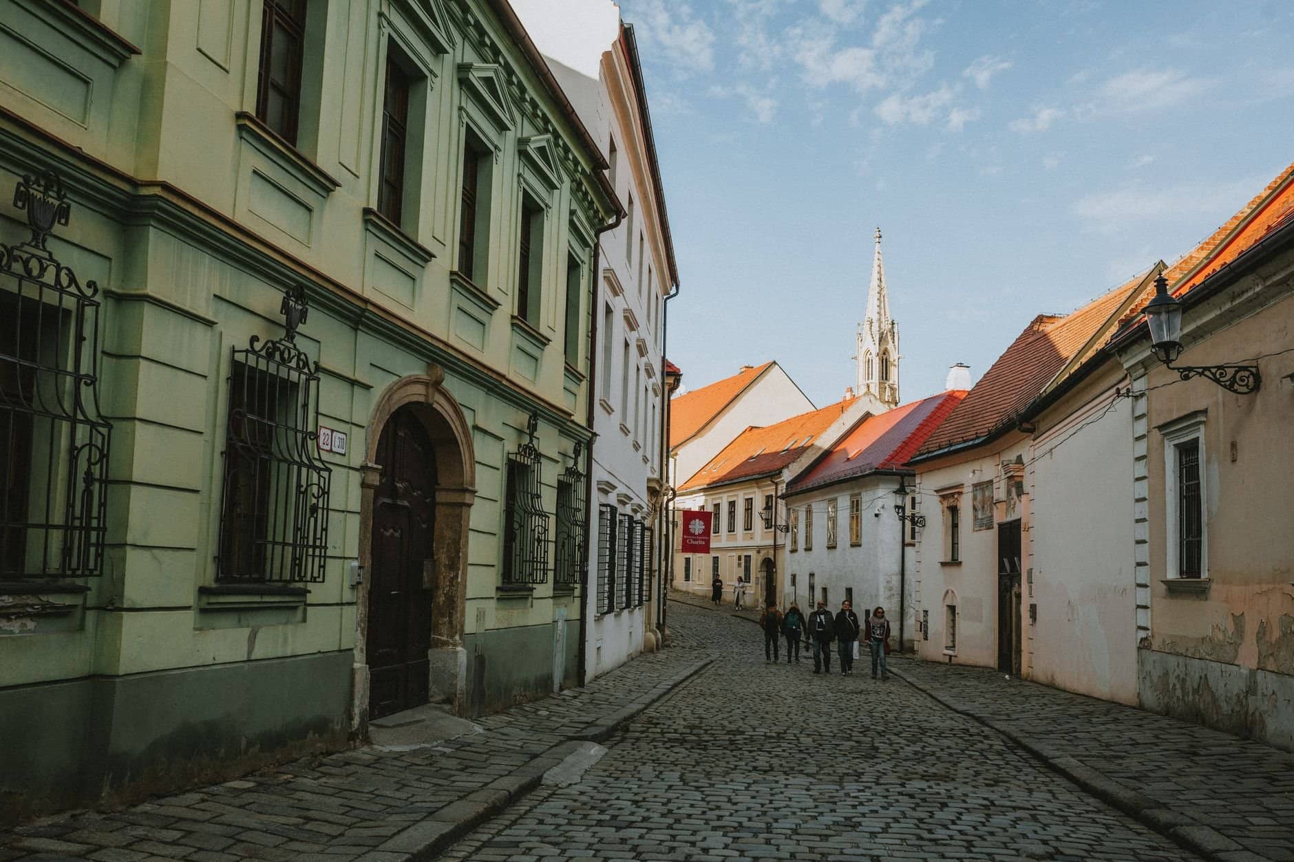Charming cobblestone street in Old Town Bratislava with historic architecture and pedestrians.