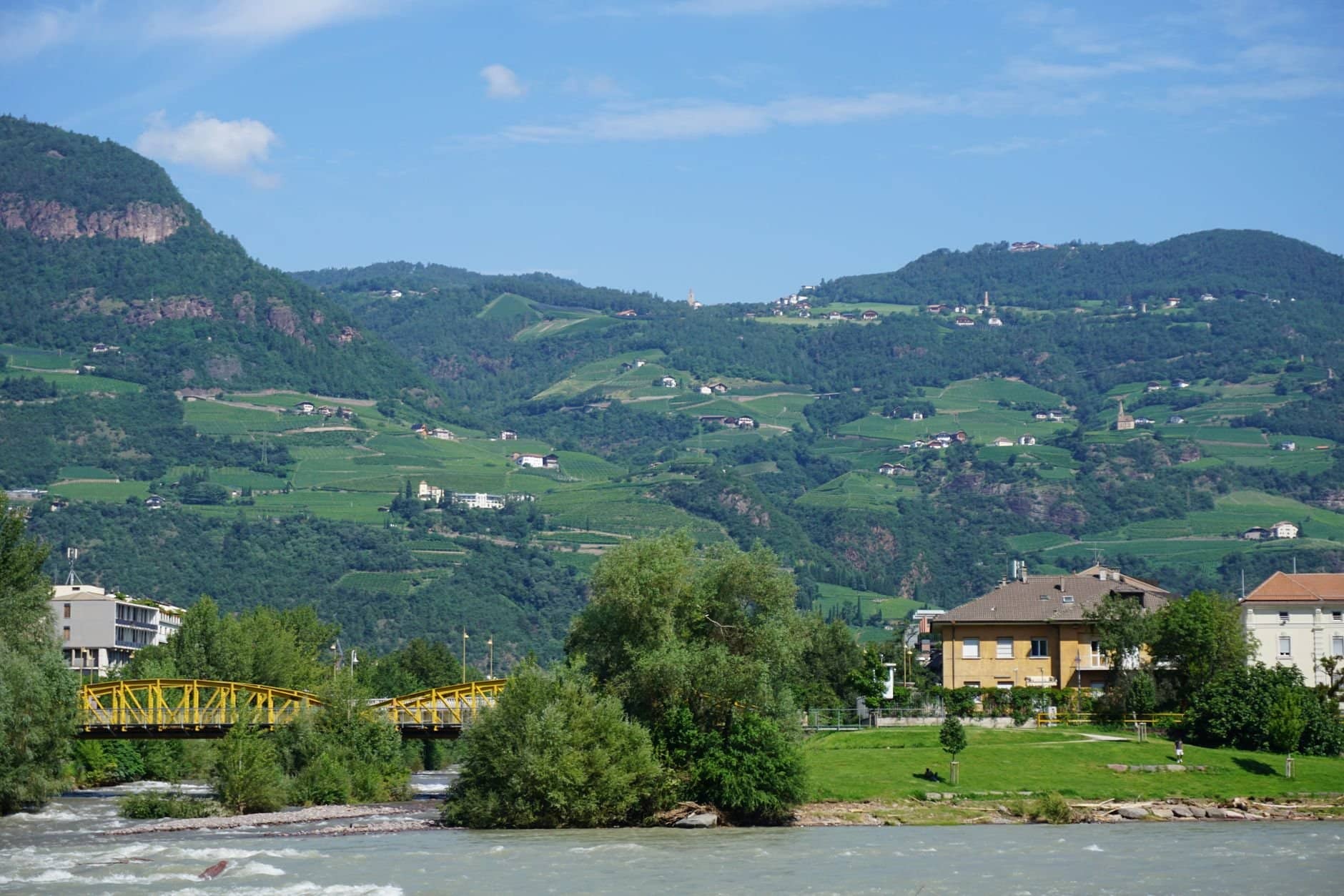A serene village nestled in lush green hills with vibrant trees and a flowing river.