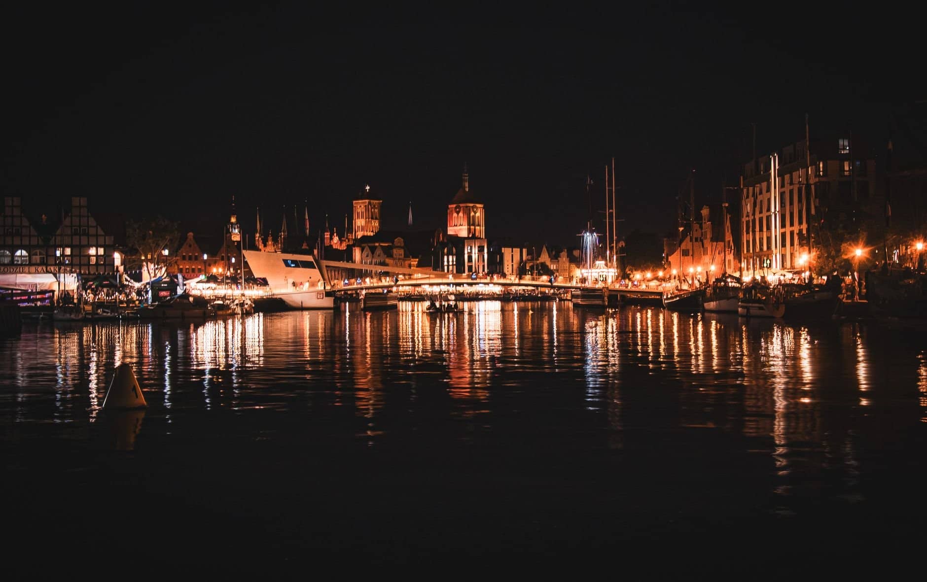Stunning nighttime view of Gdańsk's old town with lights reflecting off the Motlawa River.