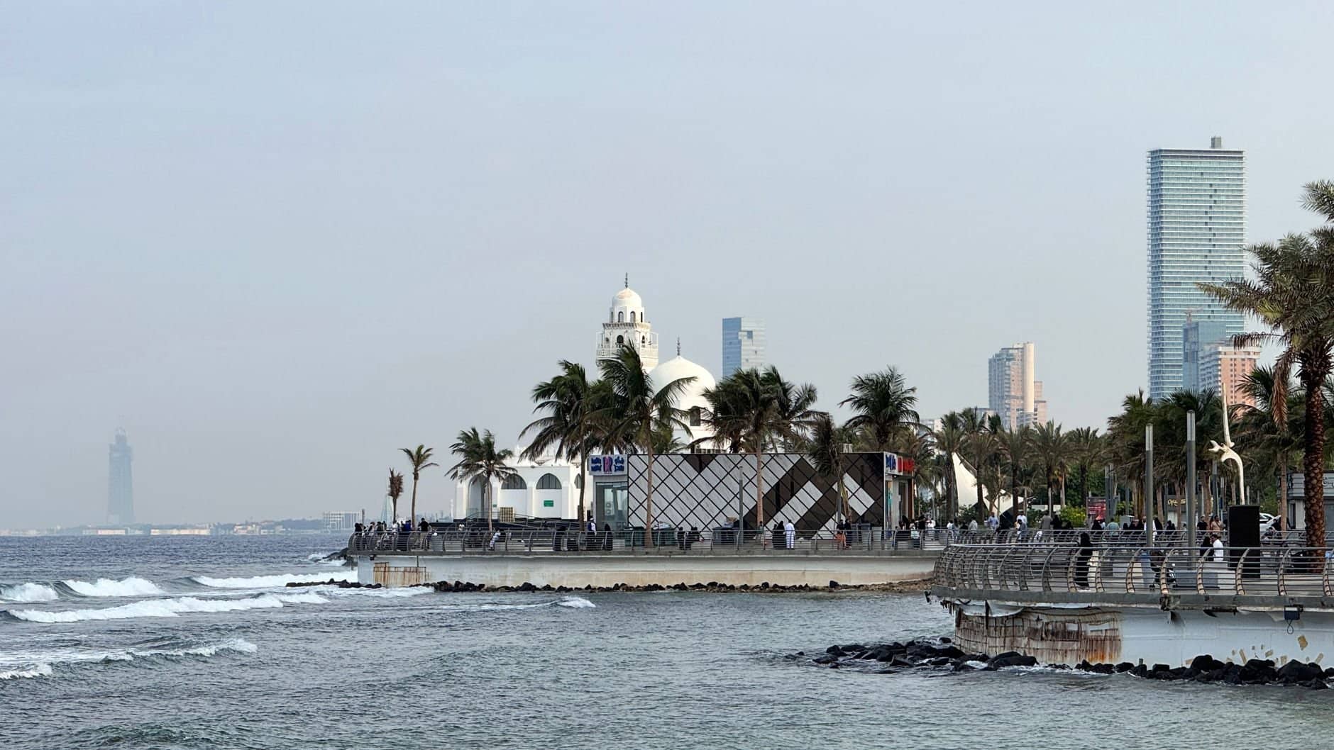 Morning view of Jeddah Corniche with palm trees and ocean waves, capturing Saudi Arabia's coastal beauty.