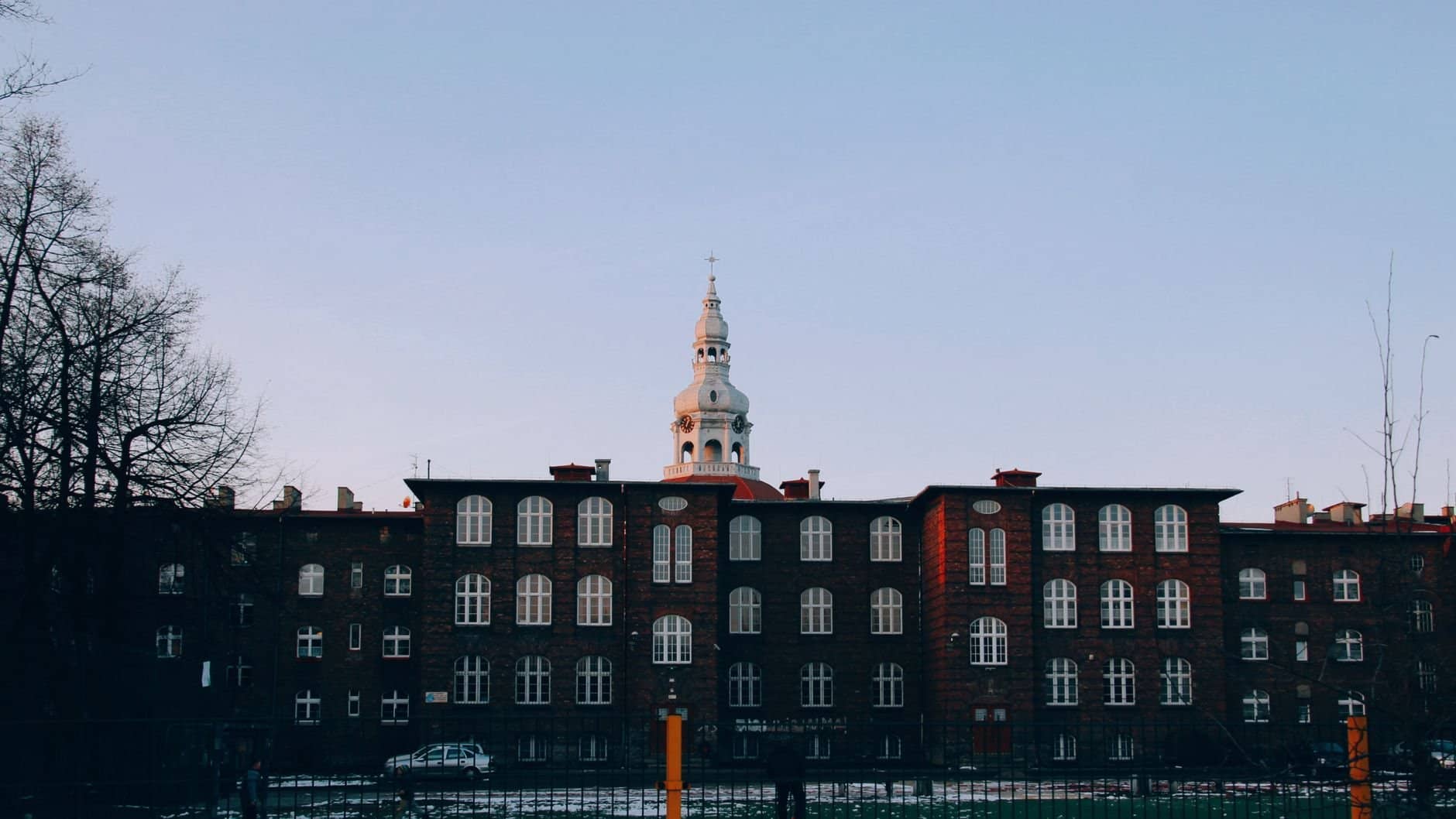 Twilight view of a historic building with a tower in Katowice, Poland.