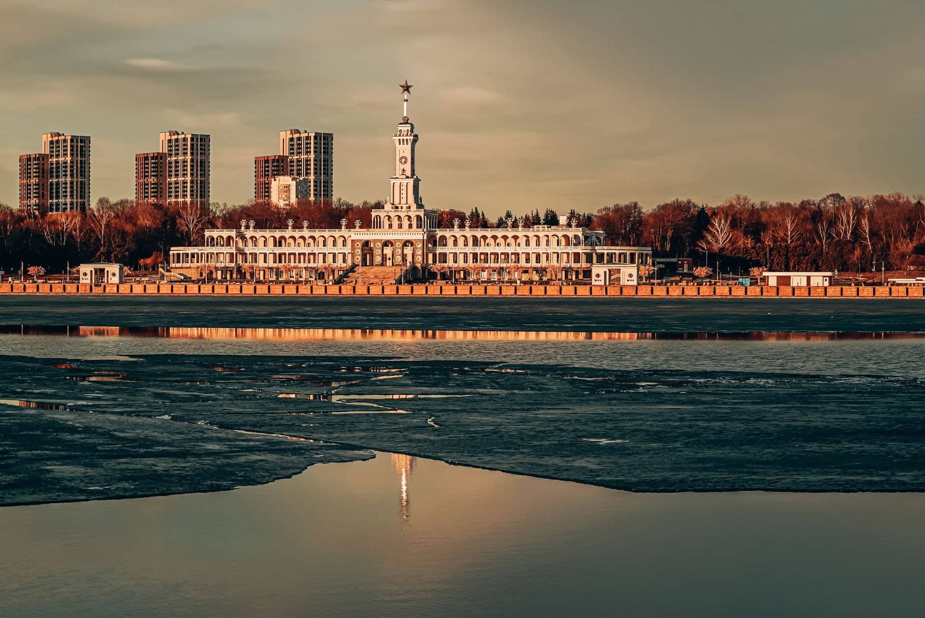 Stunning view of Severnyy Rechnoy Vokzal and Moscow skyline reflecting in the river at sunset.