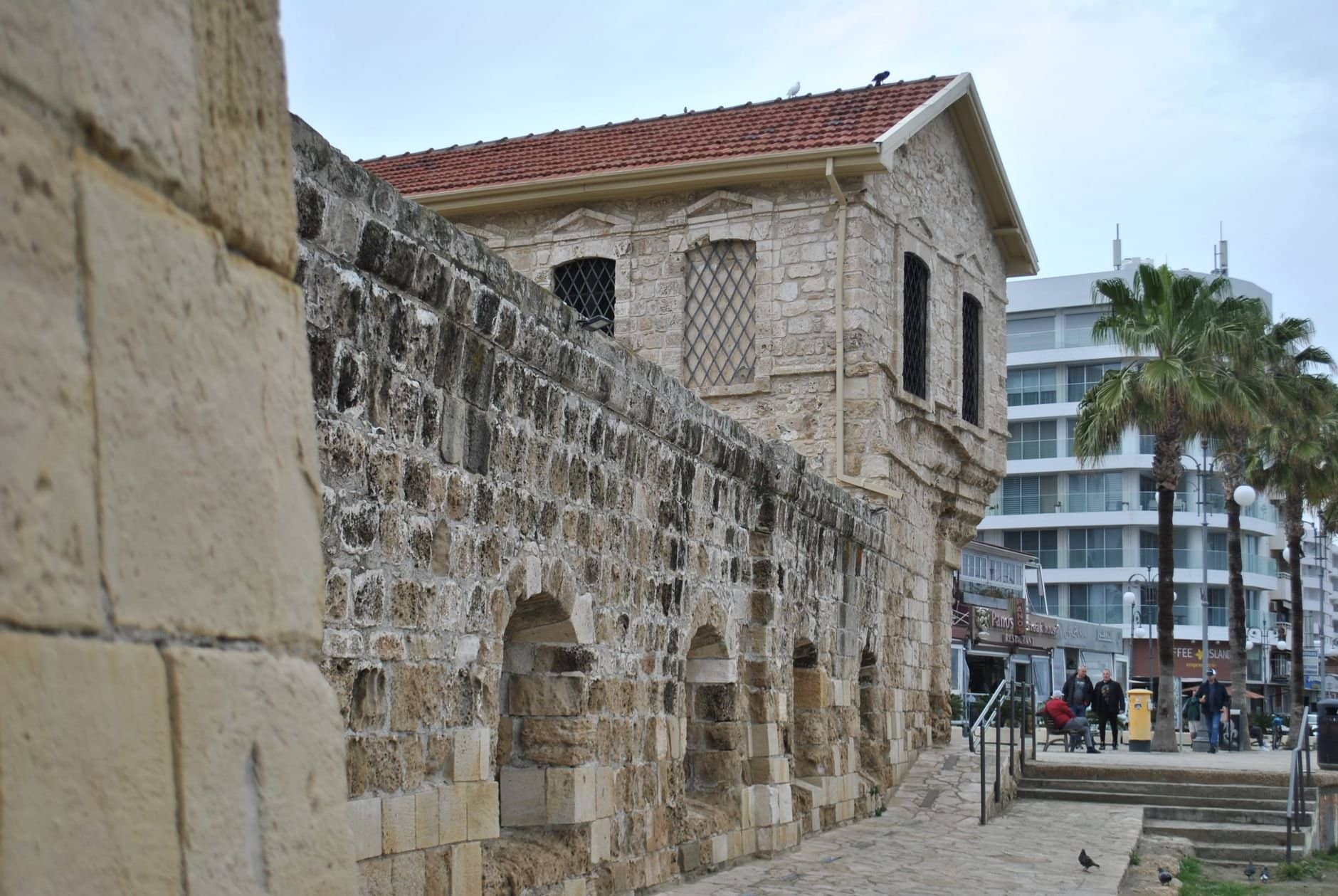 Ancient stone building in Larnaca, Cyprus, with a modern urban background.