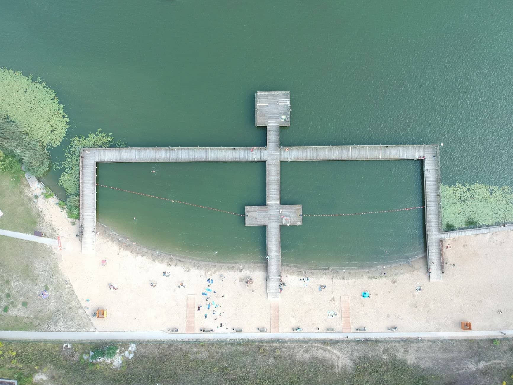 Drone shot of a wooden pier over coastal waters in Poland, showcasing unique geometry.