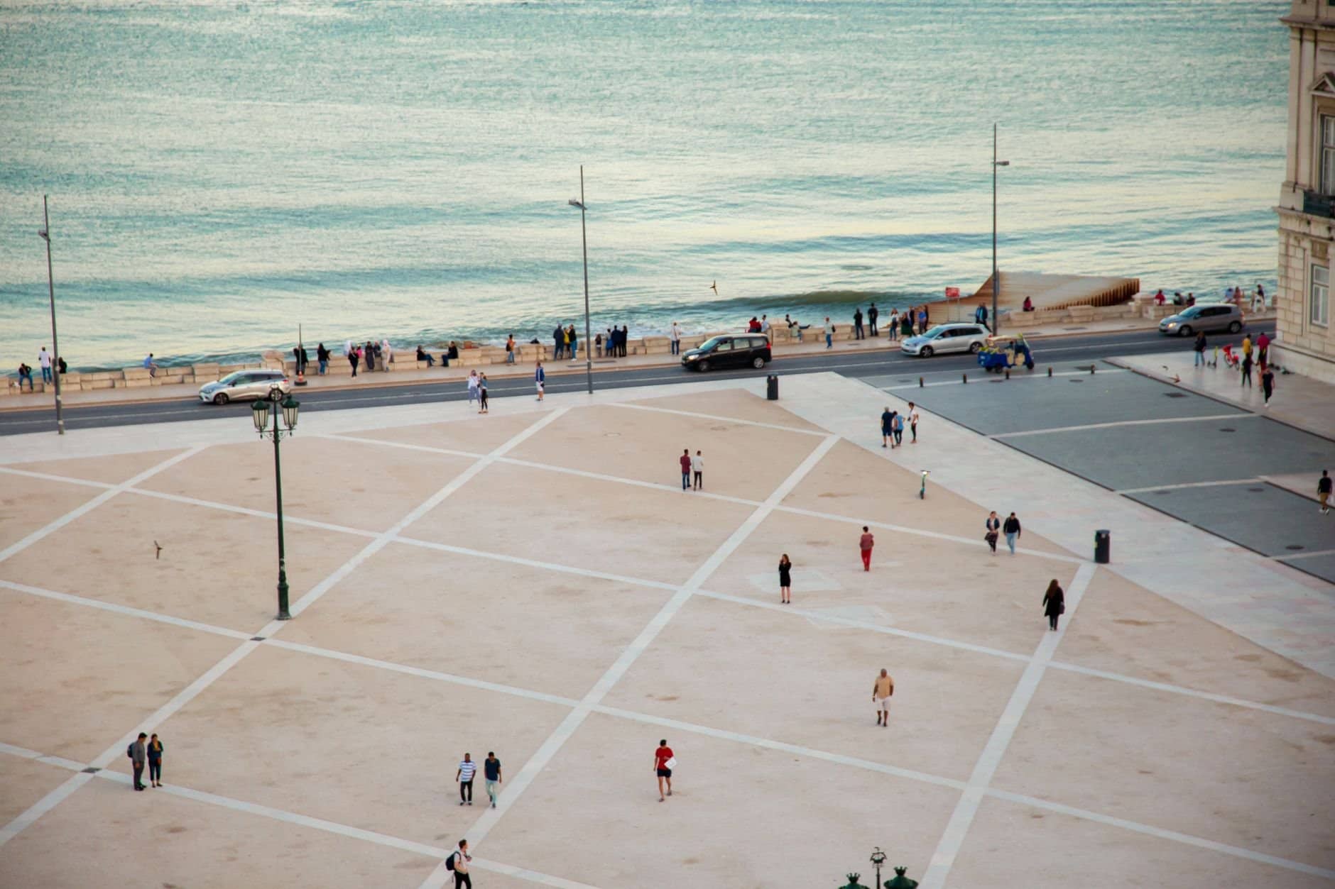 High angle citizens strolling on vast public square near rippling river located in coastal city in twilight