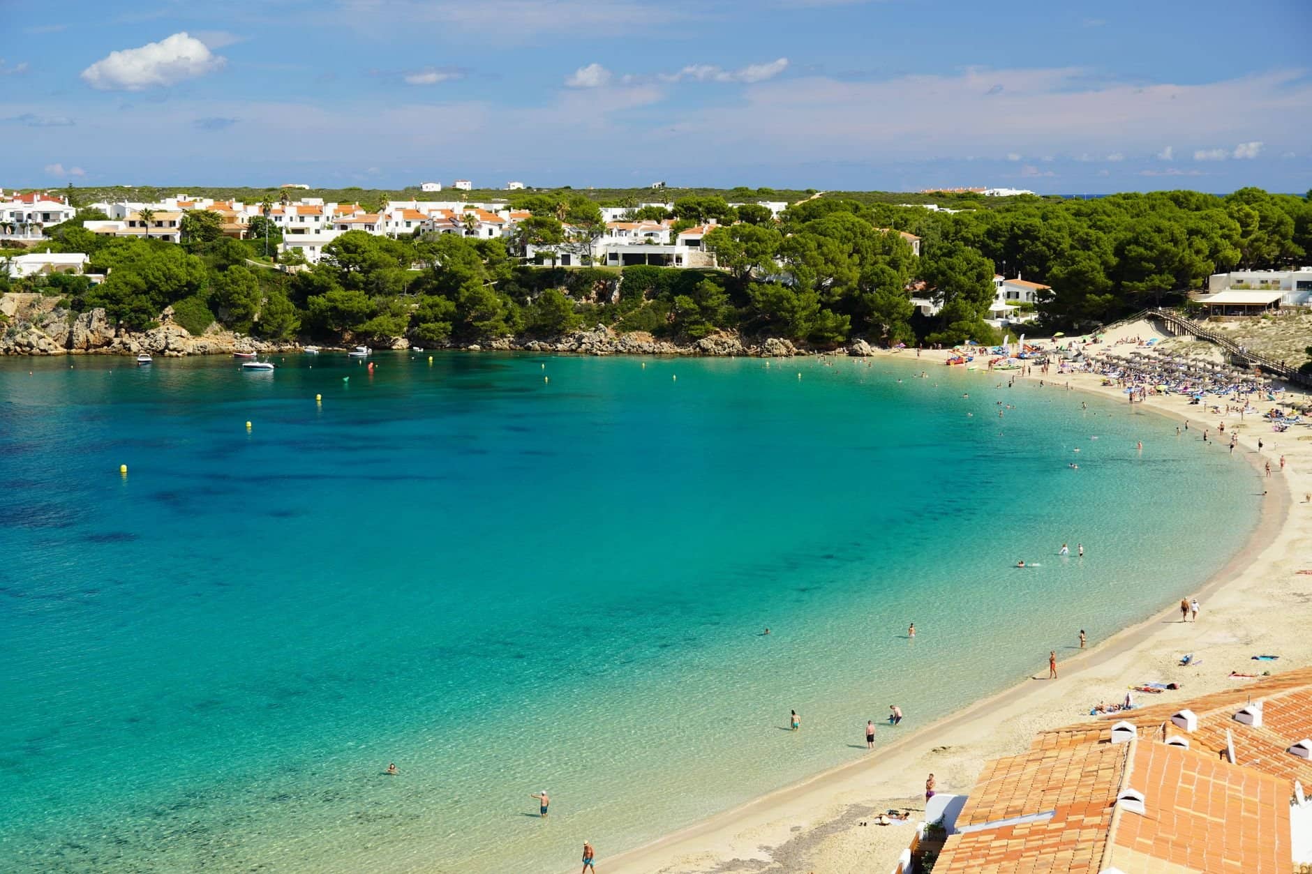 A stunning view of a beach in Menorca with clear waters and lush greenery.