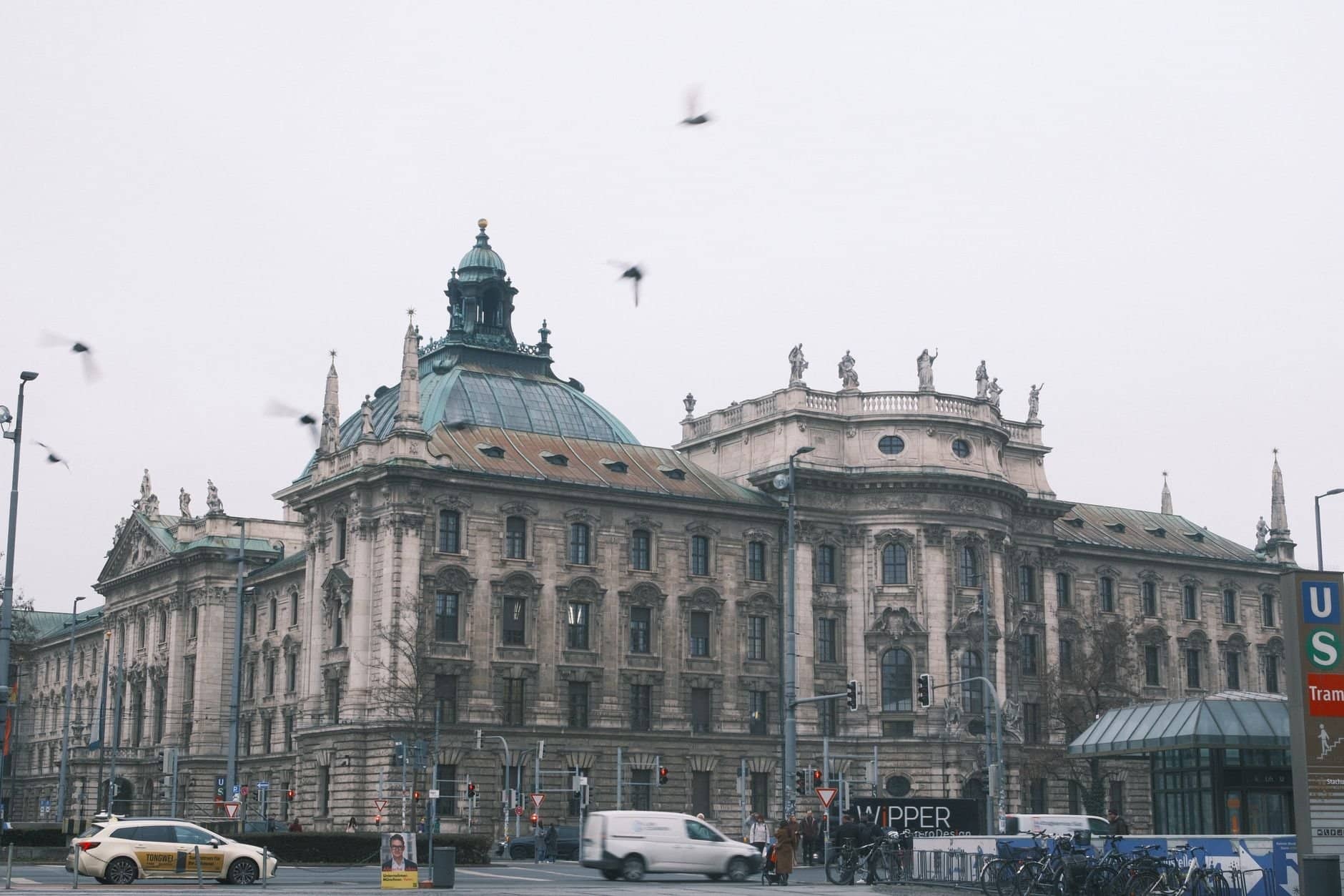 Majestic old architecture building in Munich with urban street scene on a cloudy day.