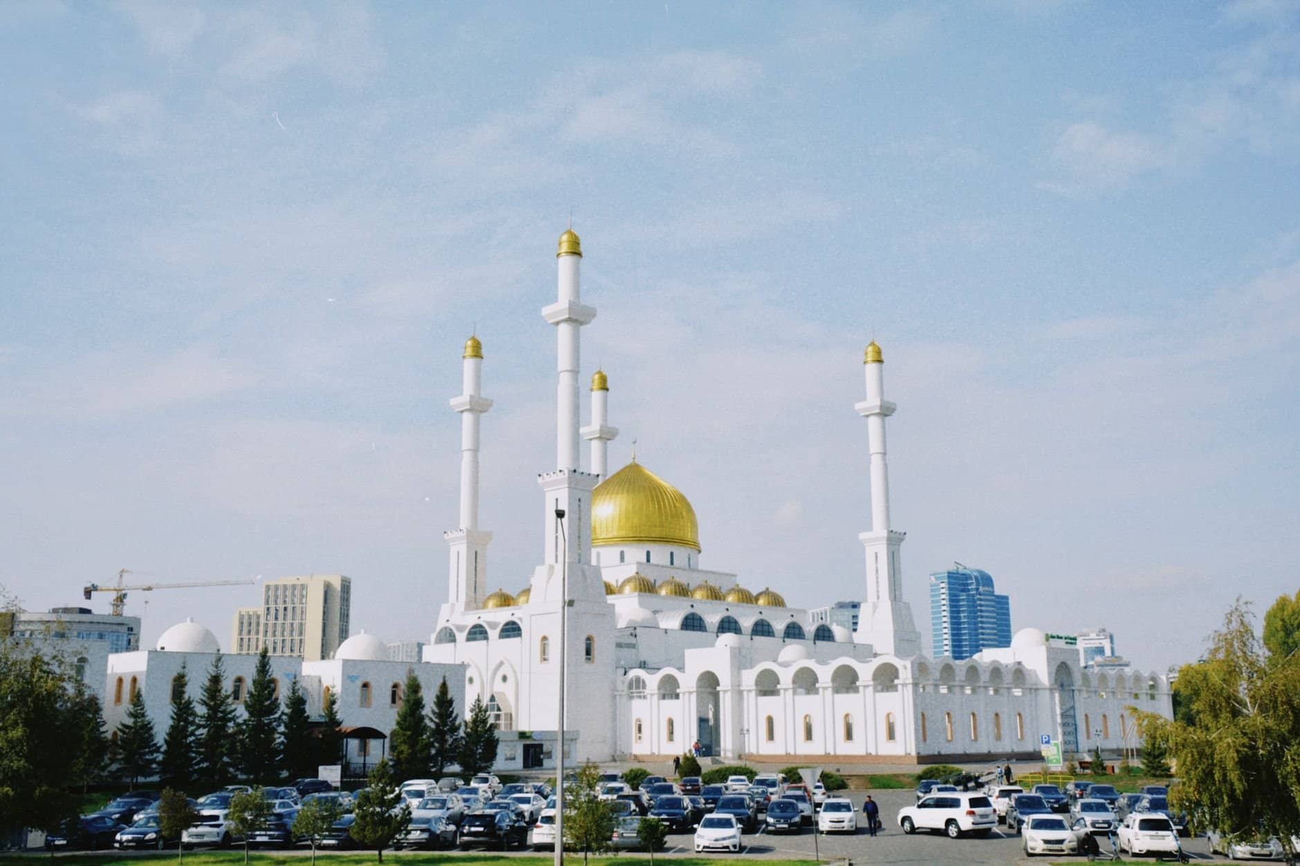 The stunning Nur-Astana Mosque in Kazakhstan with its iconic golden domes and minarets against a bright blue sky.