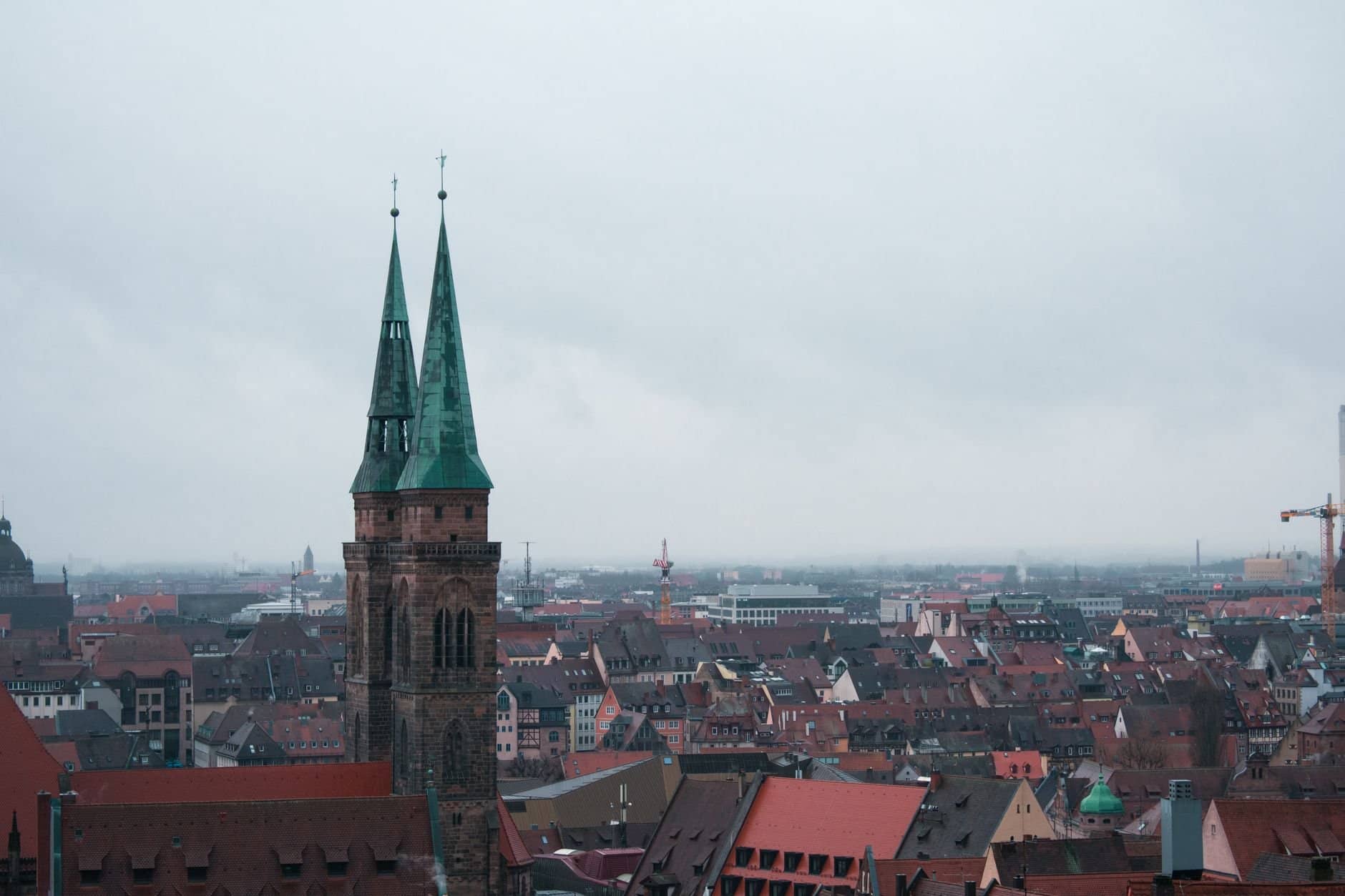 Aerial view of St. Sebaldus Church amidst the historic Nuremberg cityscape on a cloudy day.