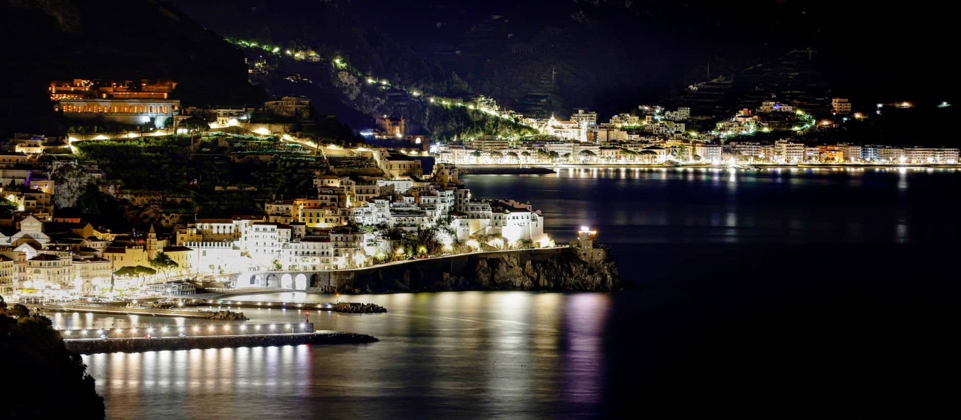 An enchanting night view of the Amalfi Coast, showcasing a beautifully lit cityscape along the coastline.