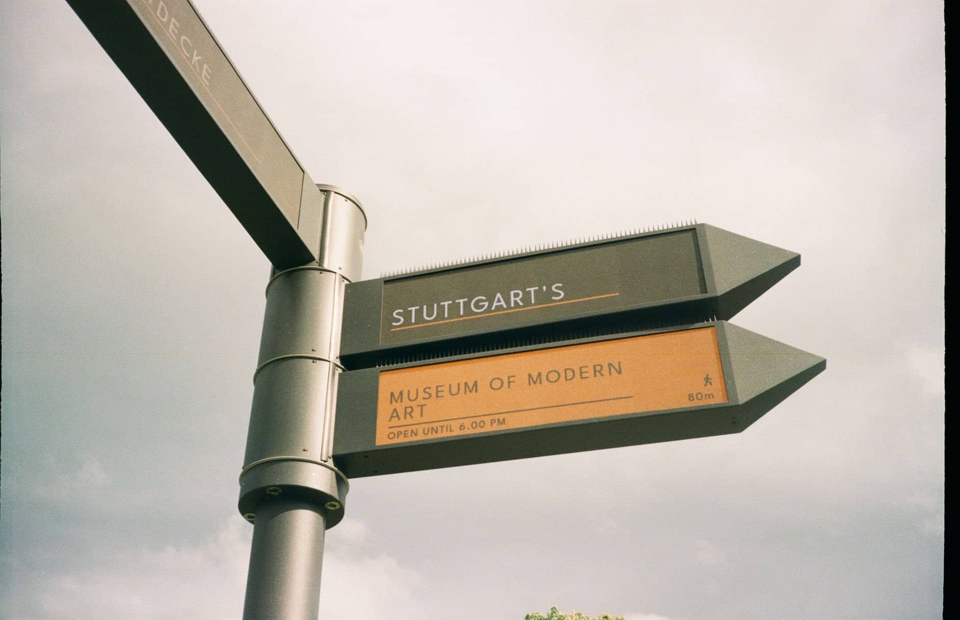 Signpost directing to Stuttgart's Museum of Modern Art under an overcast sky.