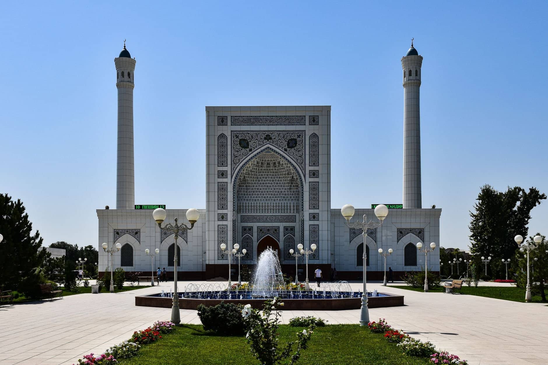 Beautiful mosque with intricate design and fountains under a clear blue sky.