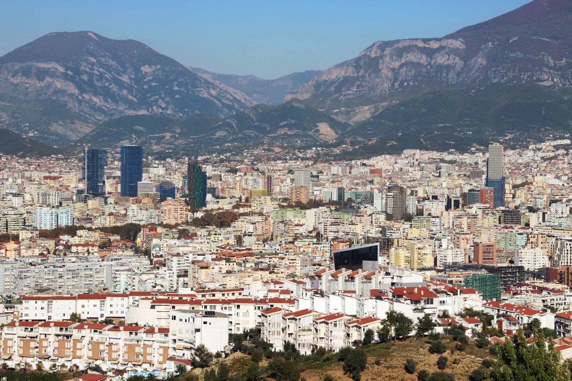 Aerial view of Tirana, Albania, featuring urban landscape and distant mountains.