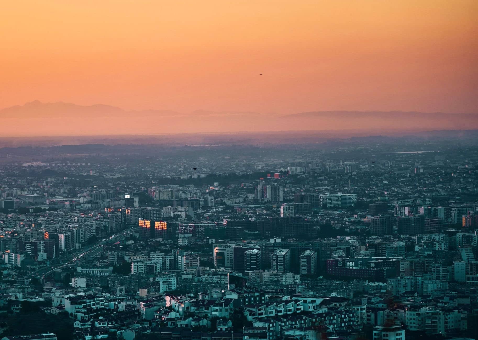 A stunning aerial shot of Tirana, Albania with vibrant orange skies during sunset. Perfect for travel and cityscape enthusiasts.