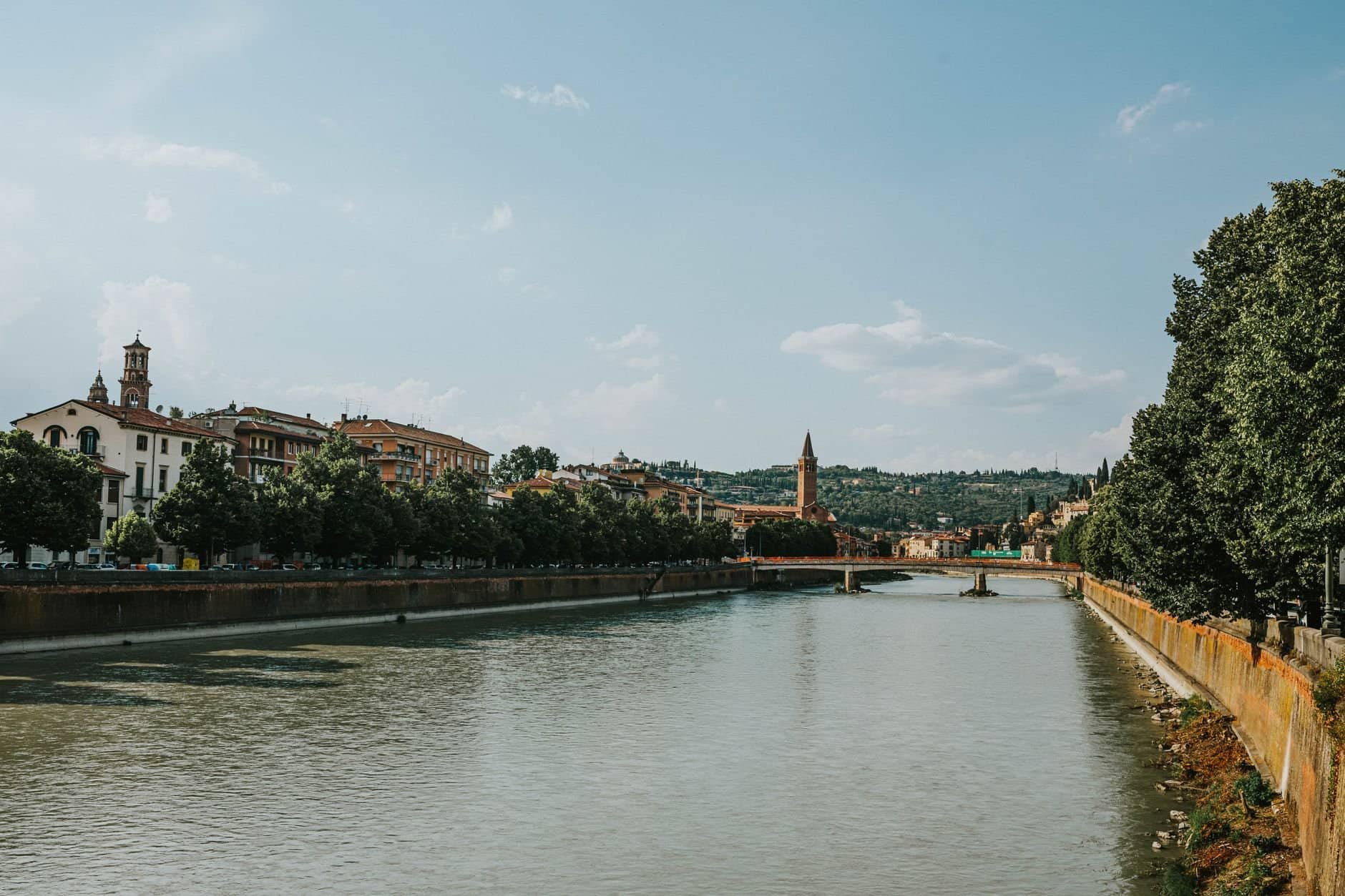 Scenic view of Verona's Adige River with iconic bridges and historic buildings under a clear sky.