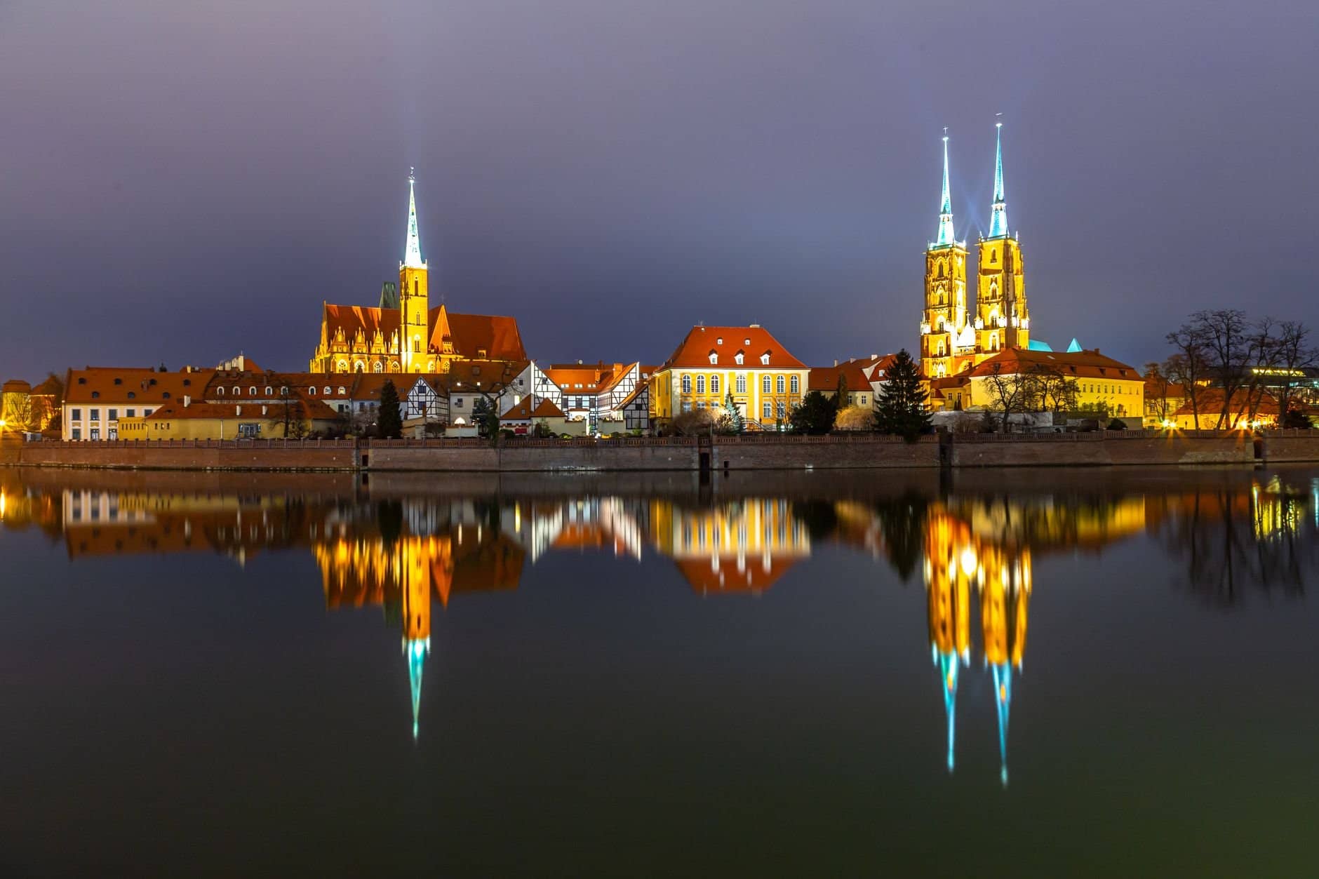 Stunning night view of Wrocław Cathedral illuminated and mirrored in the calm river.