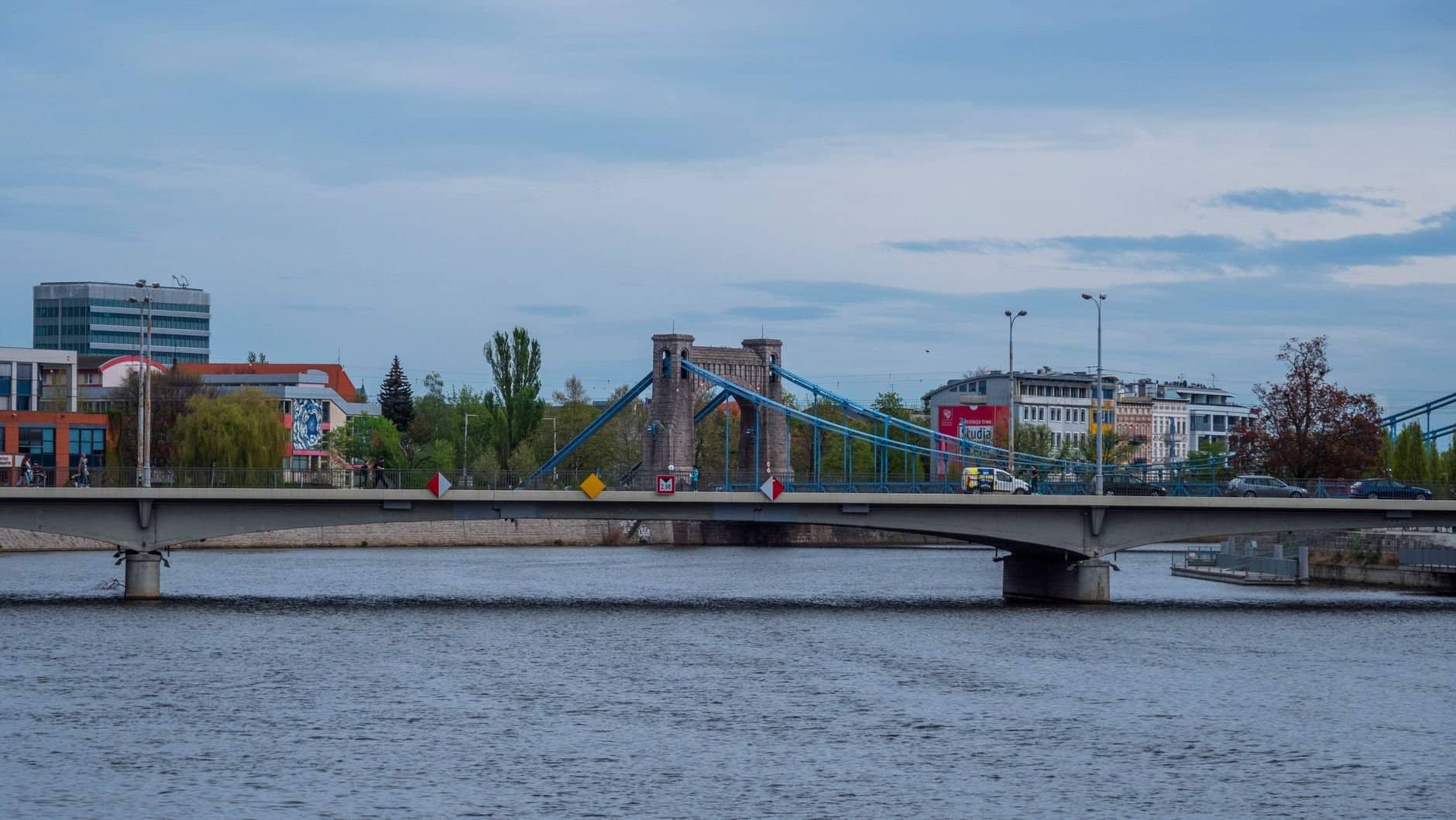 View of Grunwald Bridge with city buildings by the river.