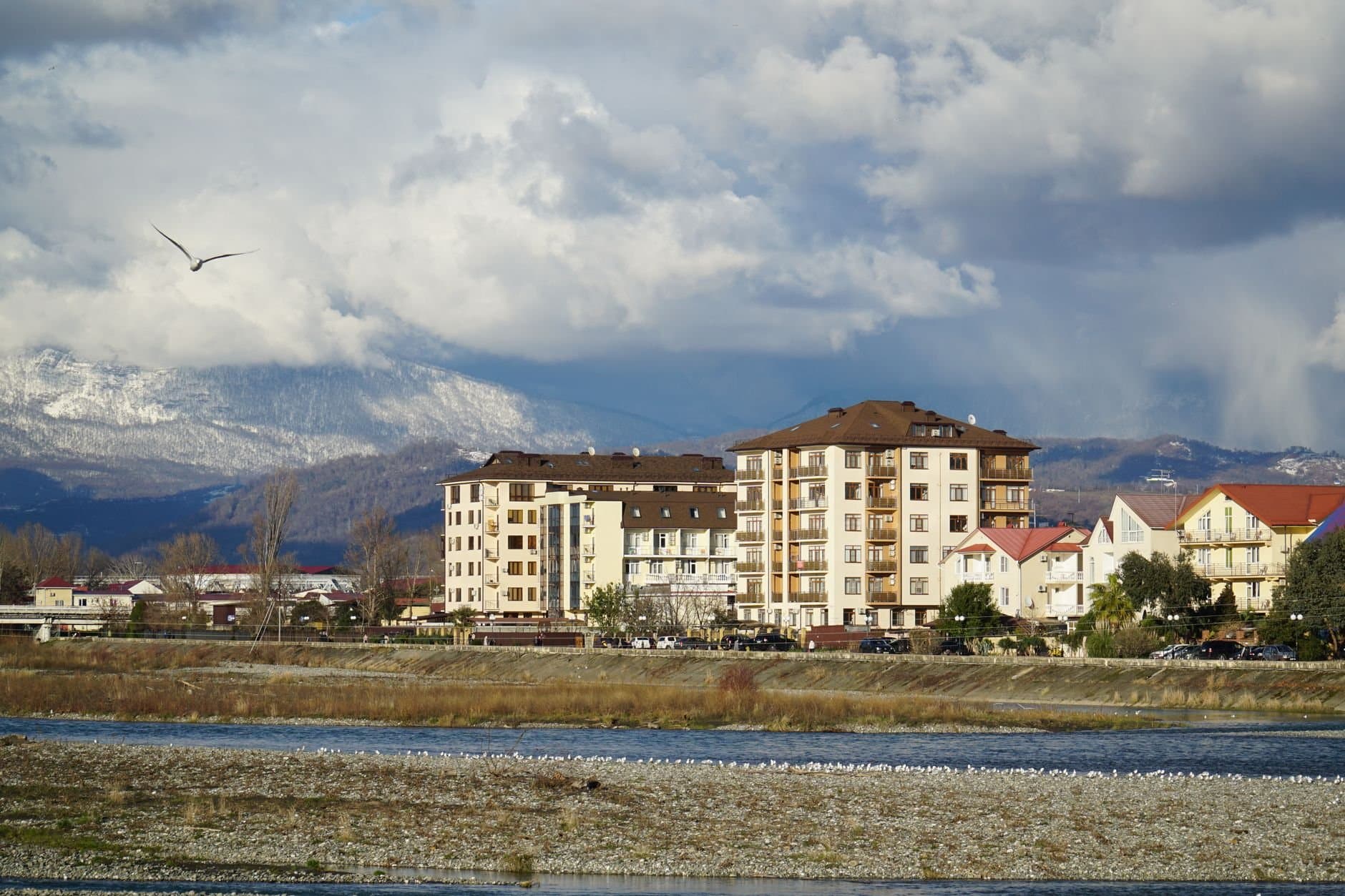 Picturesque view of Adler town in Russia, showcasing buildings with a mountainous backdrop and cloudy sky.