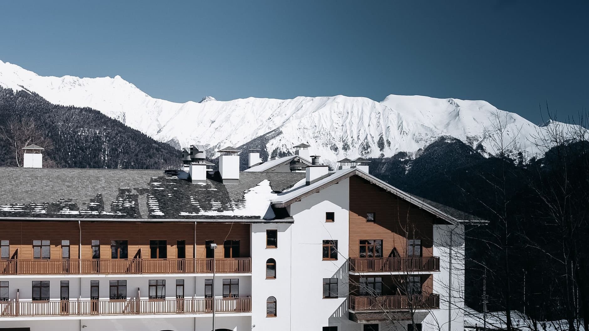 A picturesque wooden lodge nestled in snow-covered mountains near Adler, Russia.