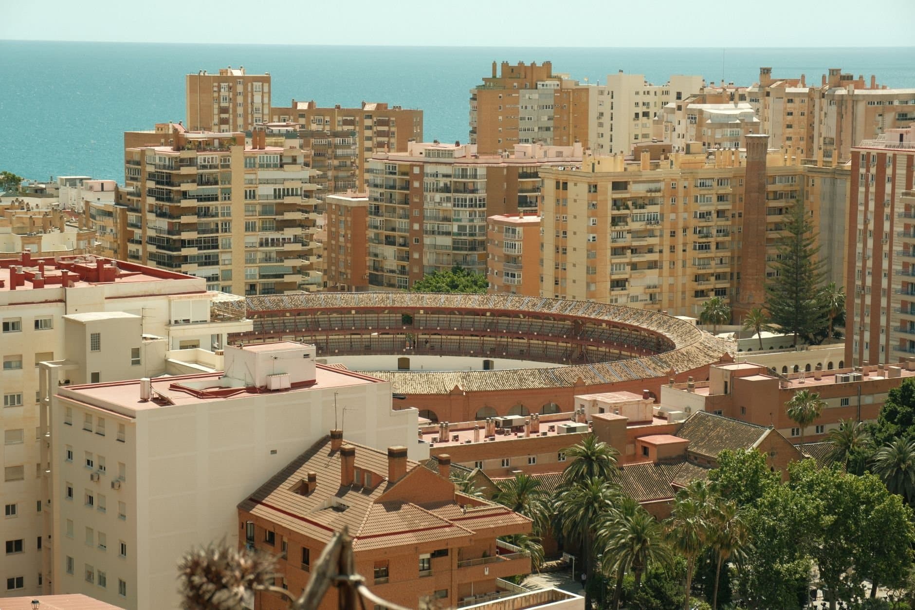 Stunning aerial shot of Malaga's bullring surrounded by modern buildings and the Mediterranean Sea.