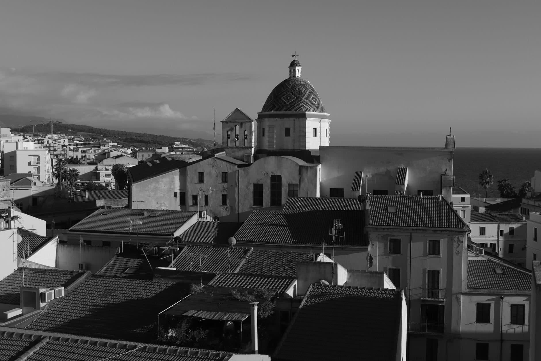 Black and white photograph capturing Alghero's iconic dome and historic cityscape.