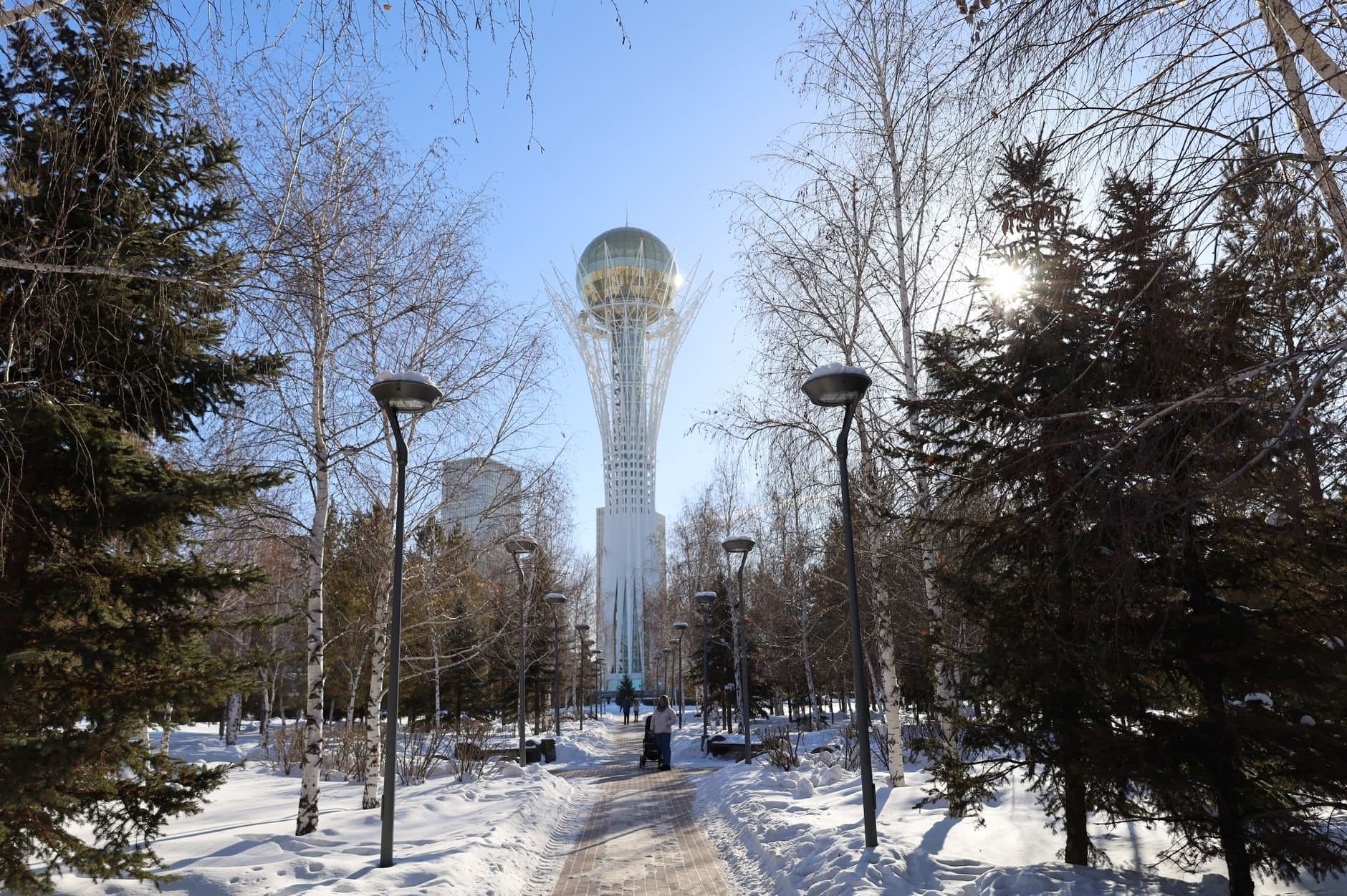 A snowy view of Baiterek Tower surrounded by trees in Nur-Sultan, Kazakhstan.