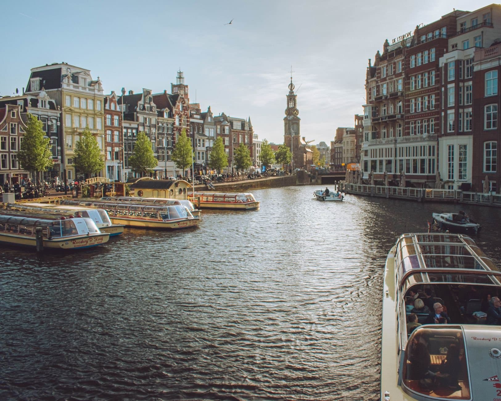 Charming view of Amsterdam's canals with tour boats and historic buildings, capturing the essence of the city.