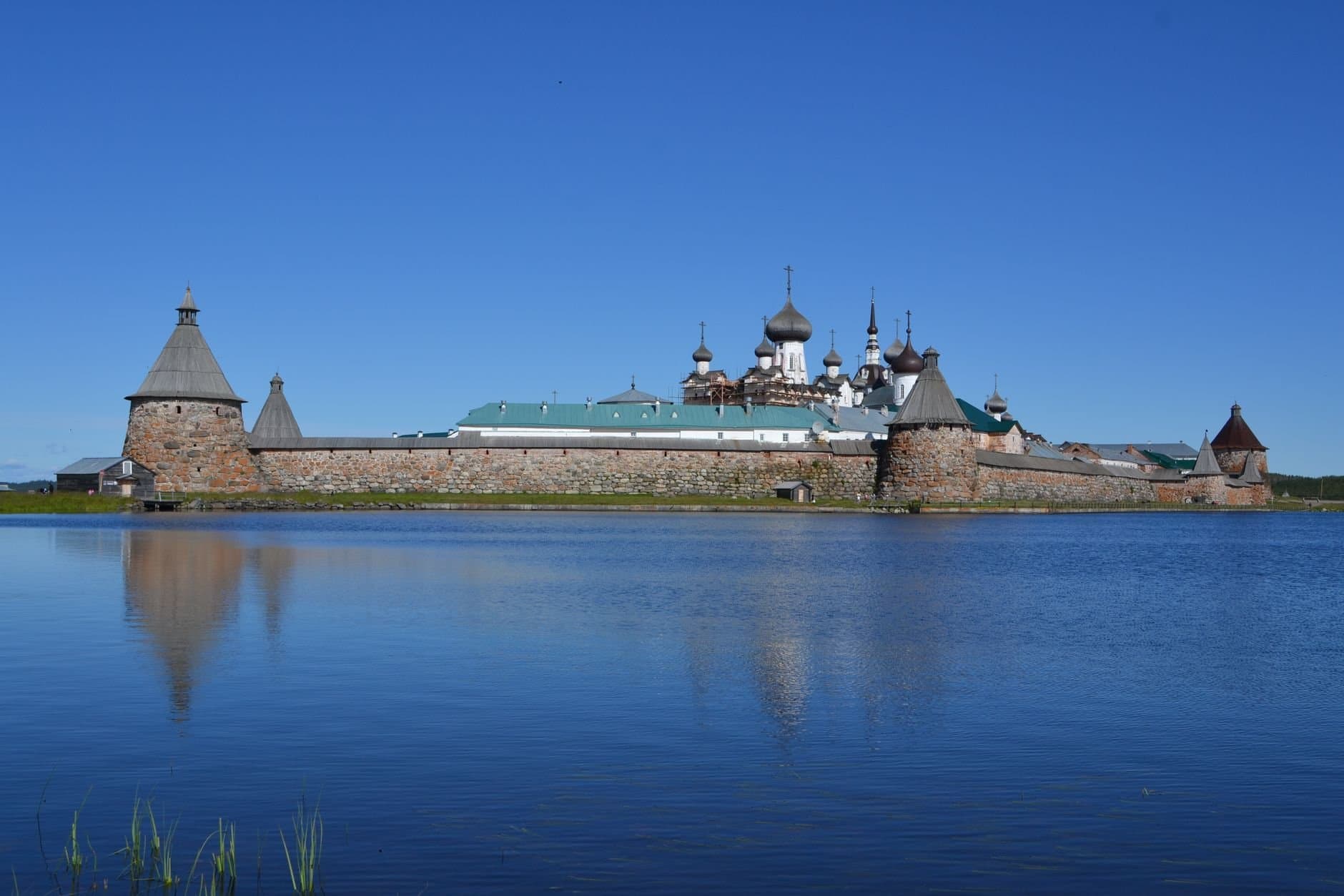 Stunning view of Solovetsky Monastery with clear sky reflections, showcasing historical architecture in Russia.