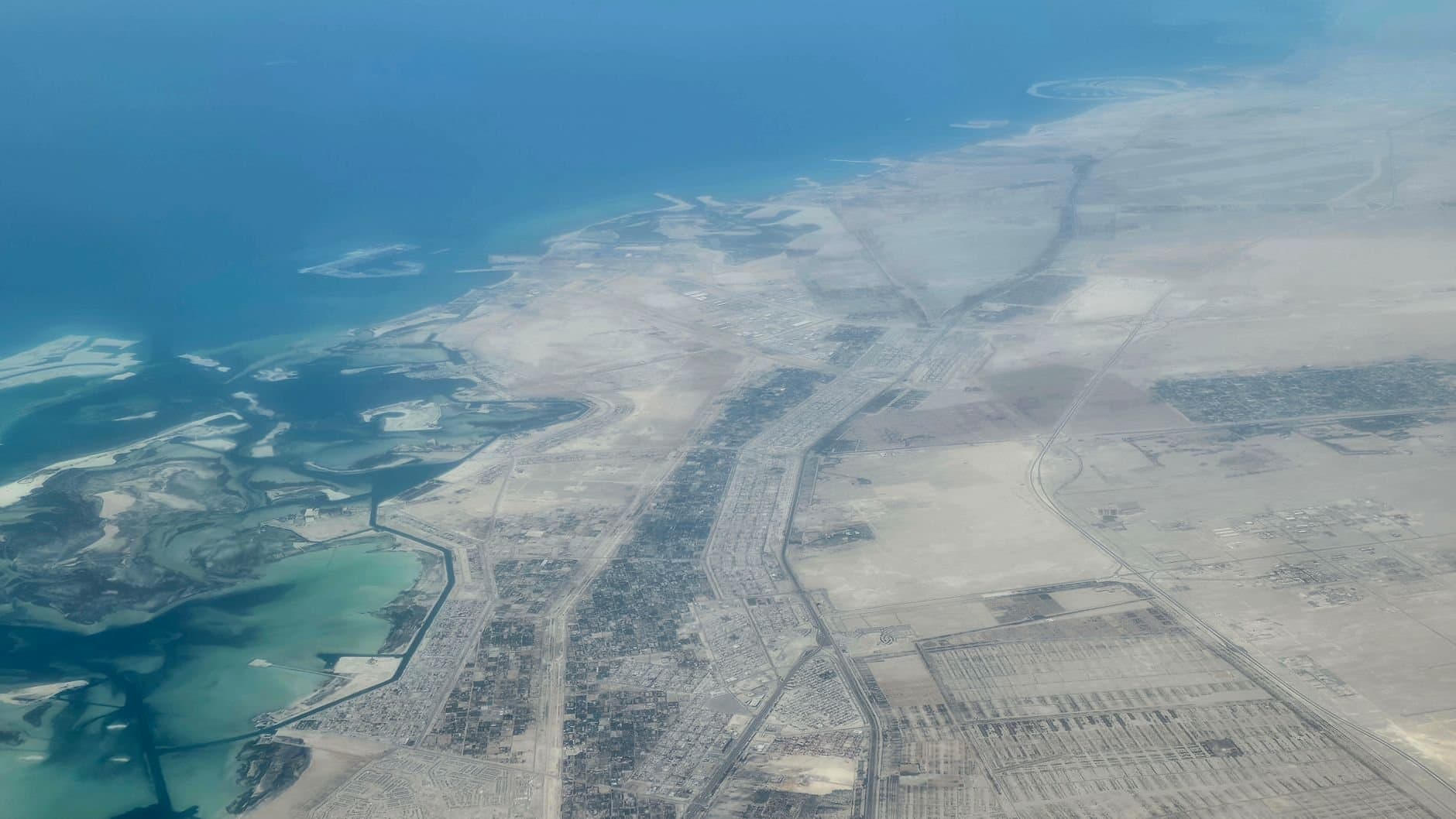 Aerial view of a coastal desert landscape with roads and settlements along the shoreline.