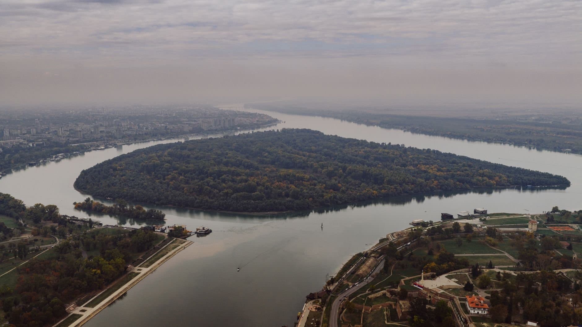 Stunning aerial shot of the river bend in Belgrade, Serbia, showcasing lush greenery and cityscape.