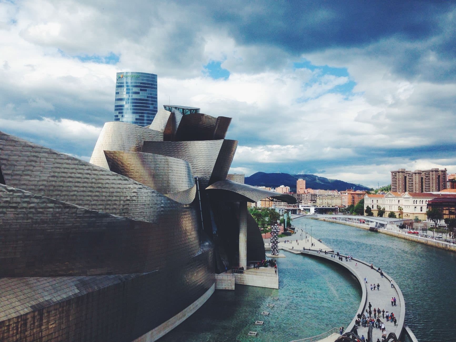 Dynamic architecture of Guggenheim Museum Bilbao with riverside view and cityscape.