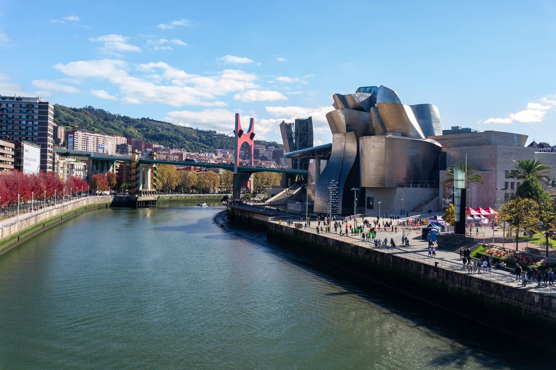 A stunning view of Guggenheim Museum Bilbao alongside a scenic river and urban landscape.
