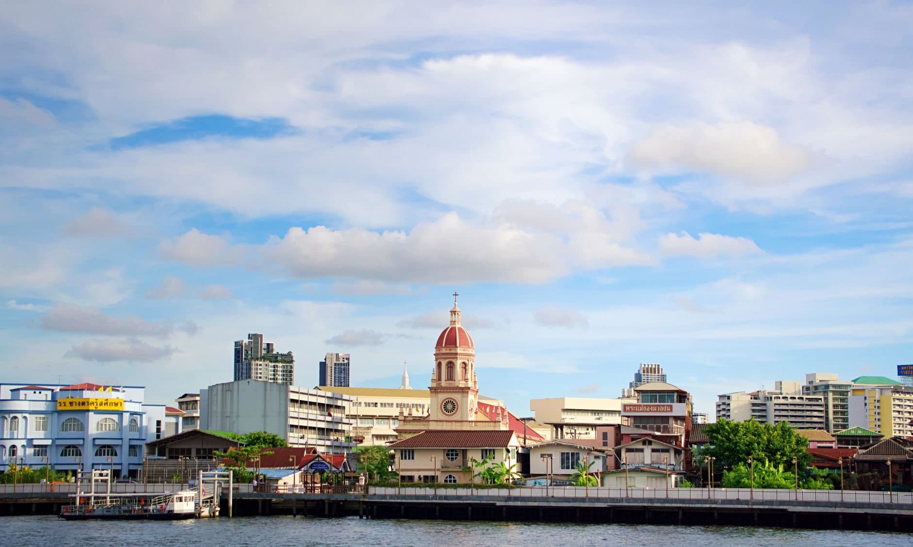 Charming riverside view in Bangkok showcasing iconic architecture under a vibrant sky.
