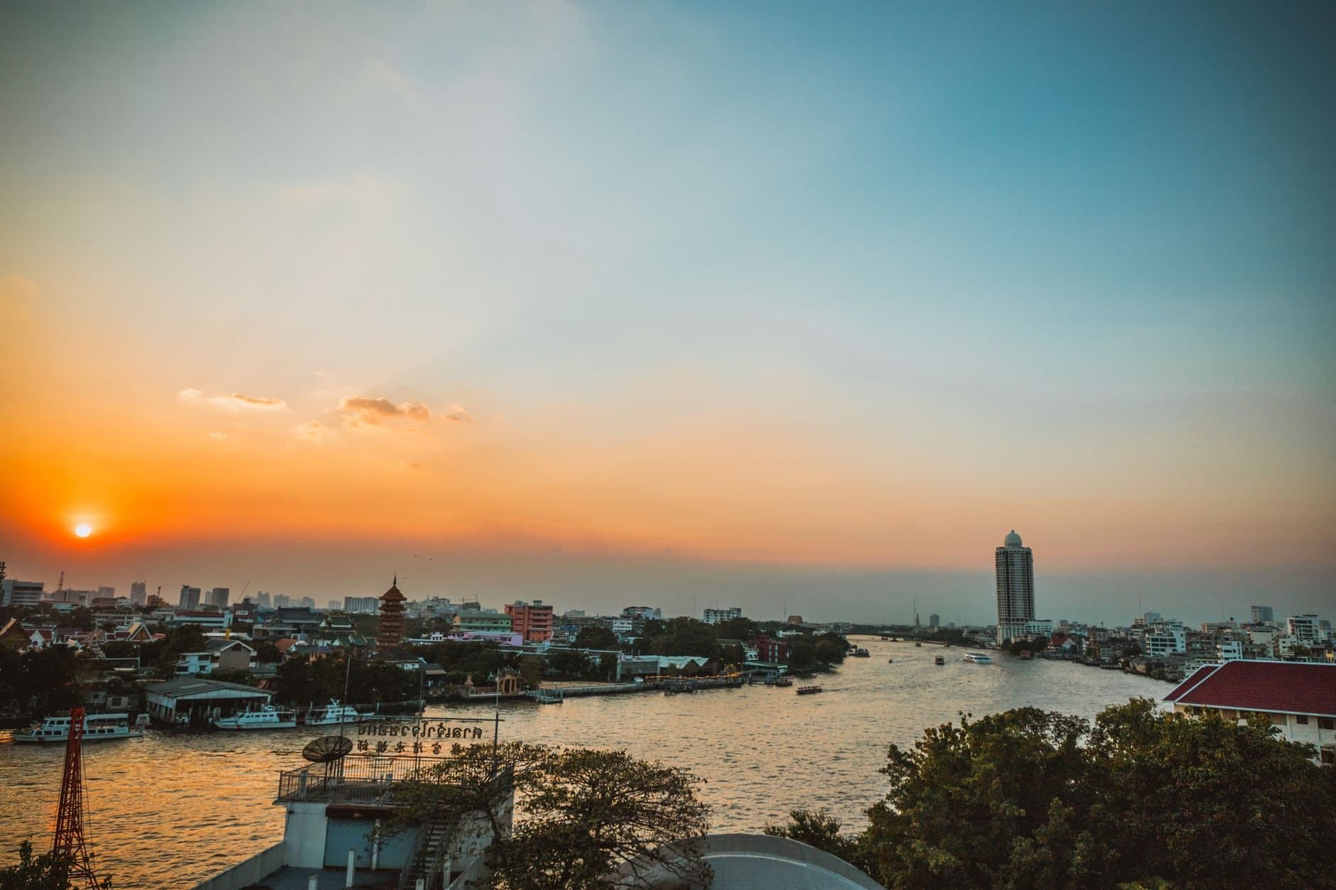 Stunning sunset view over Bangkok's Chao Phraya River with cityscape and skyline.
