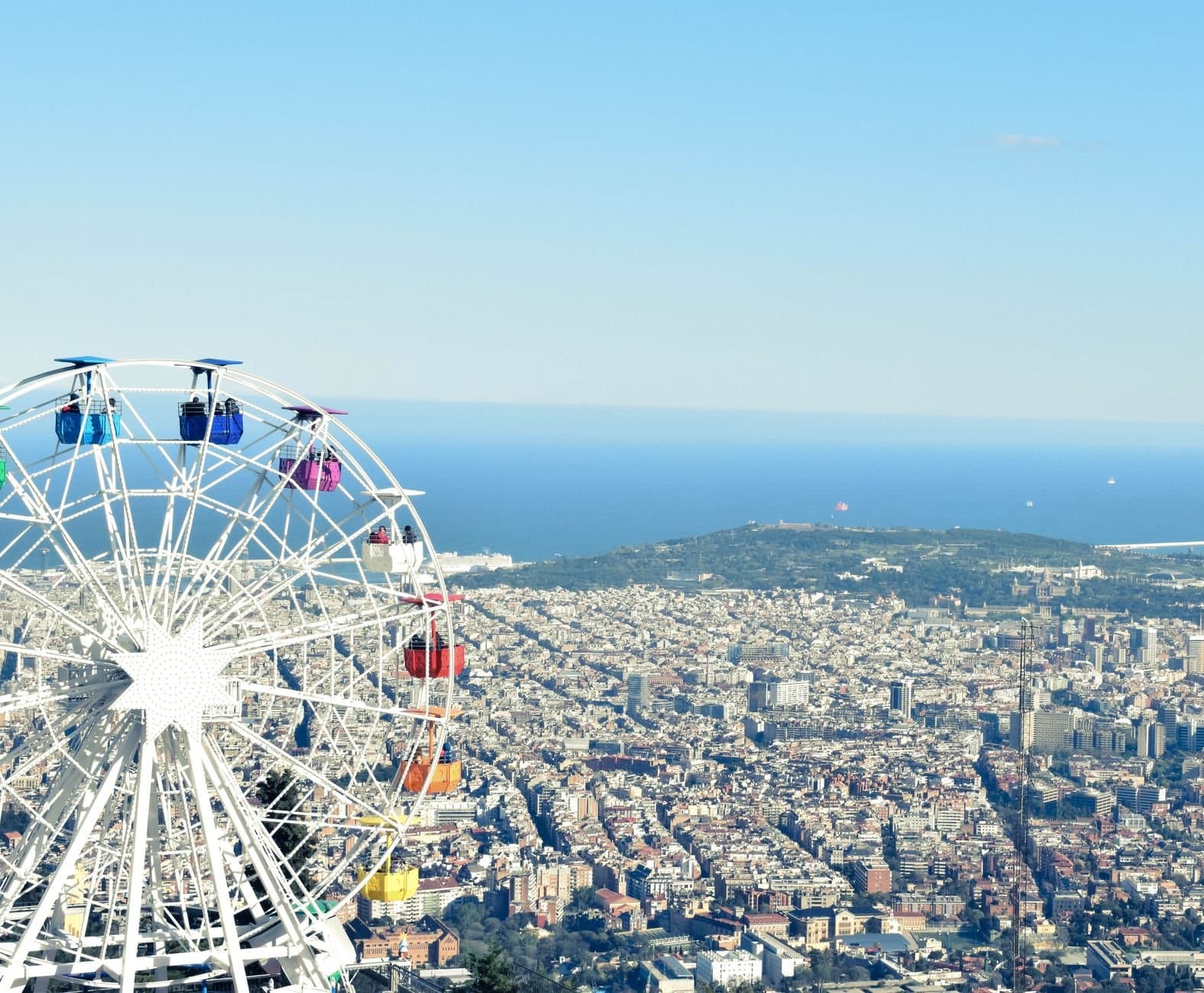 Colorful Ferris wheel with panoramic view of Barcelona city, coastline and sea.