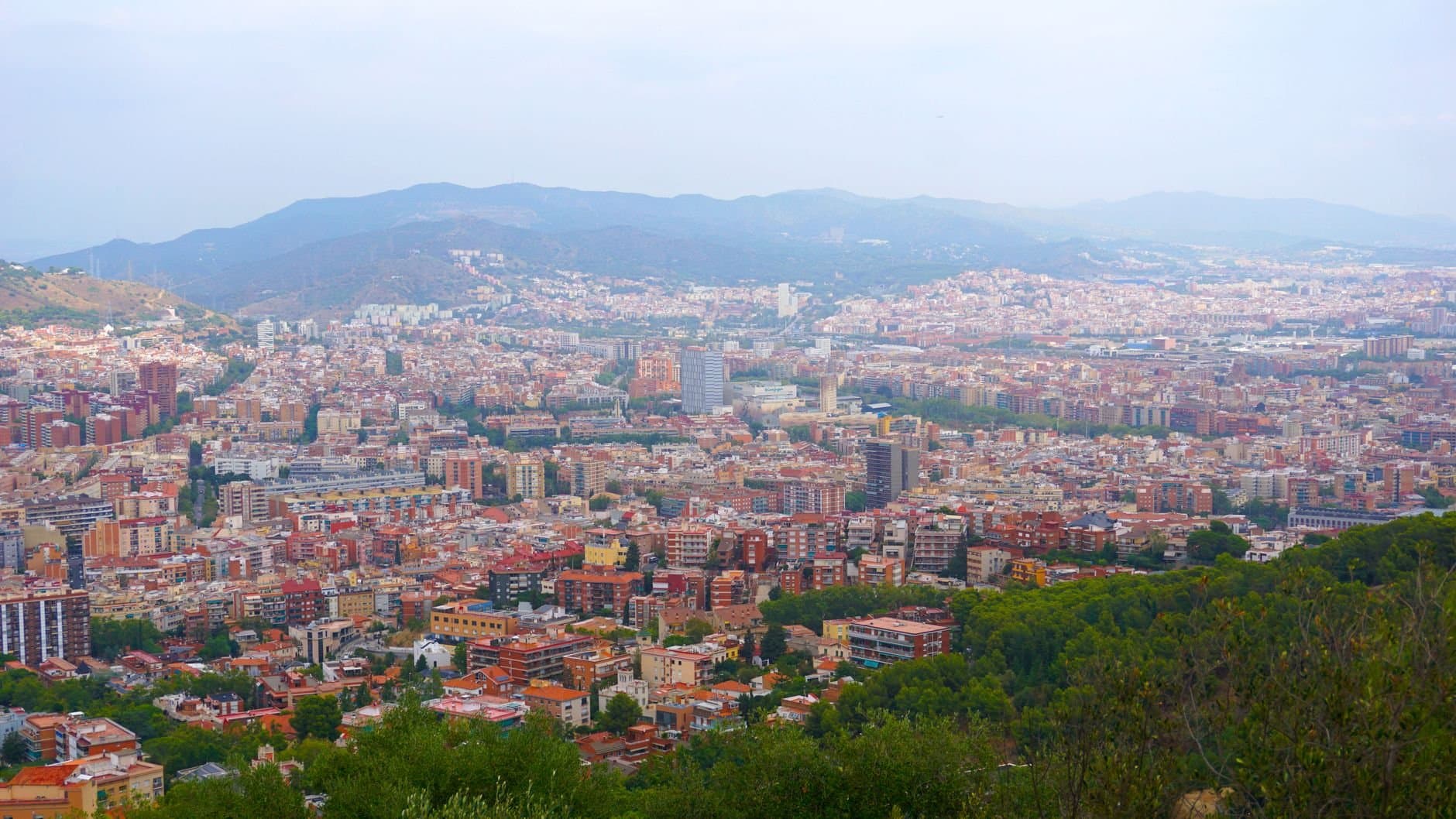 Explore a stunning aerial view of Barcelona, showcasing its vibrant architecture and mountainous backdrop.