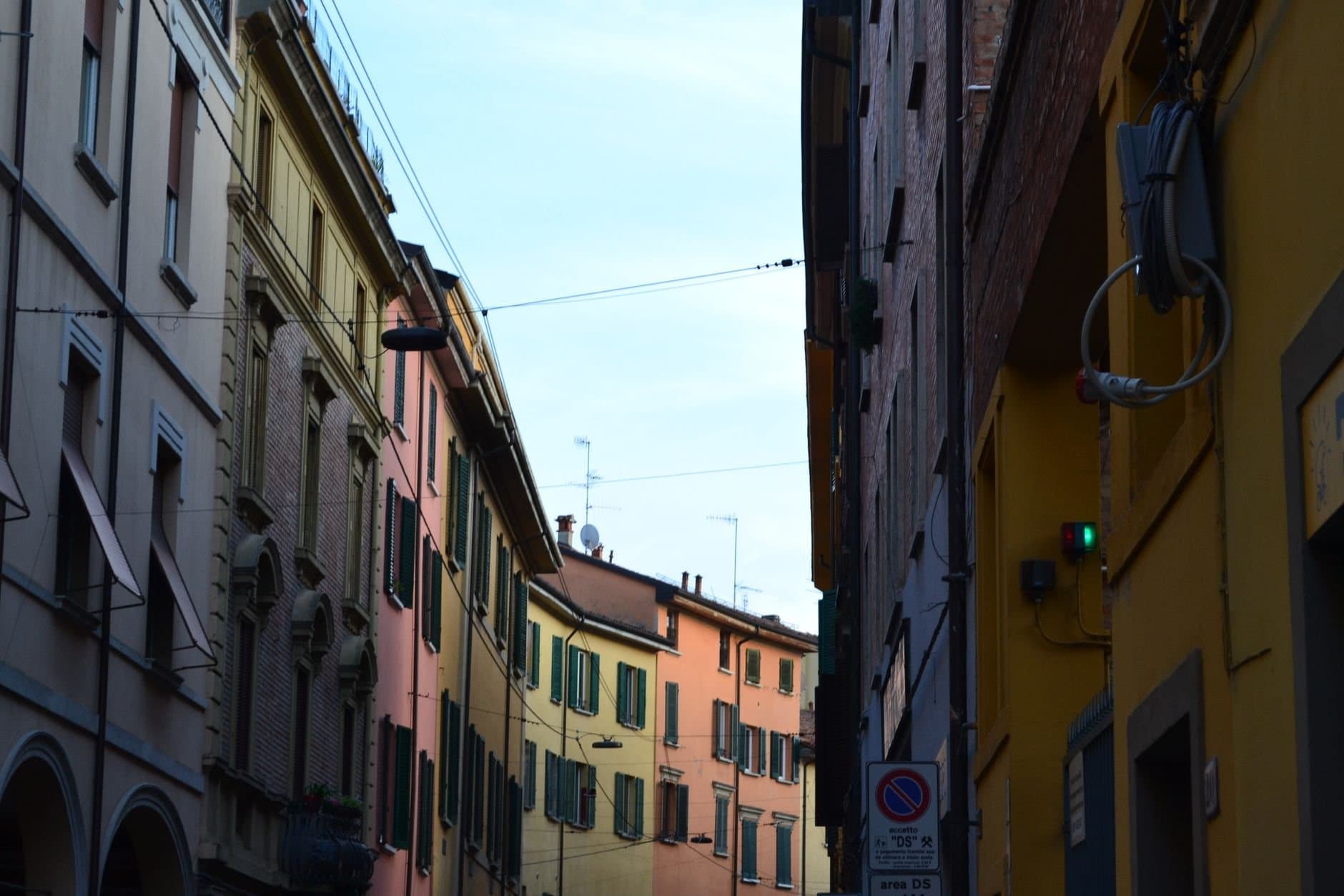 Charming view of vibrant buildings lining a narrow street in Bologna, Italy.