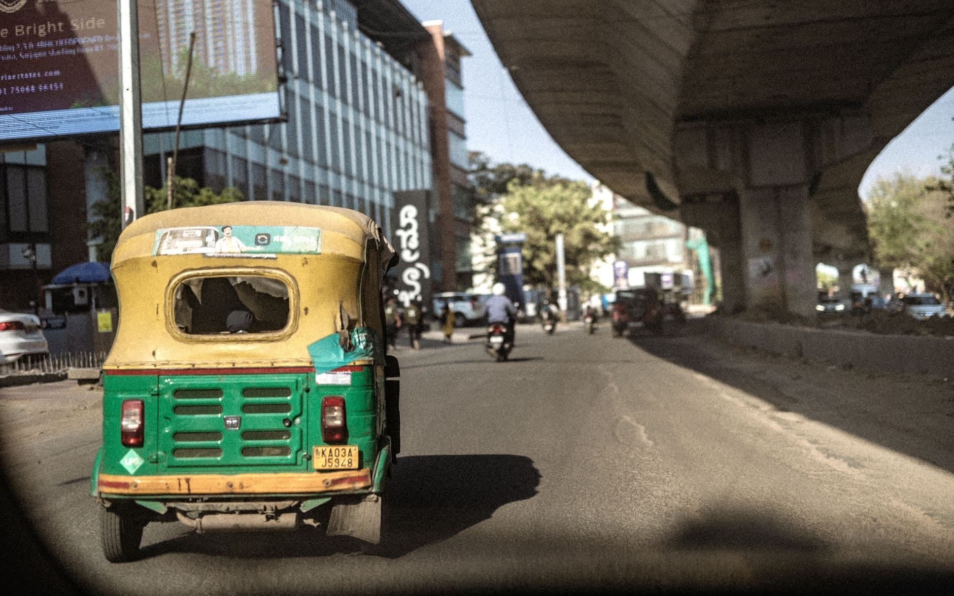 Dynamic street view in Bengaluru featuring a rickshaw and overhead bridge capturing urban life.