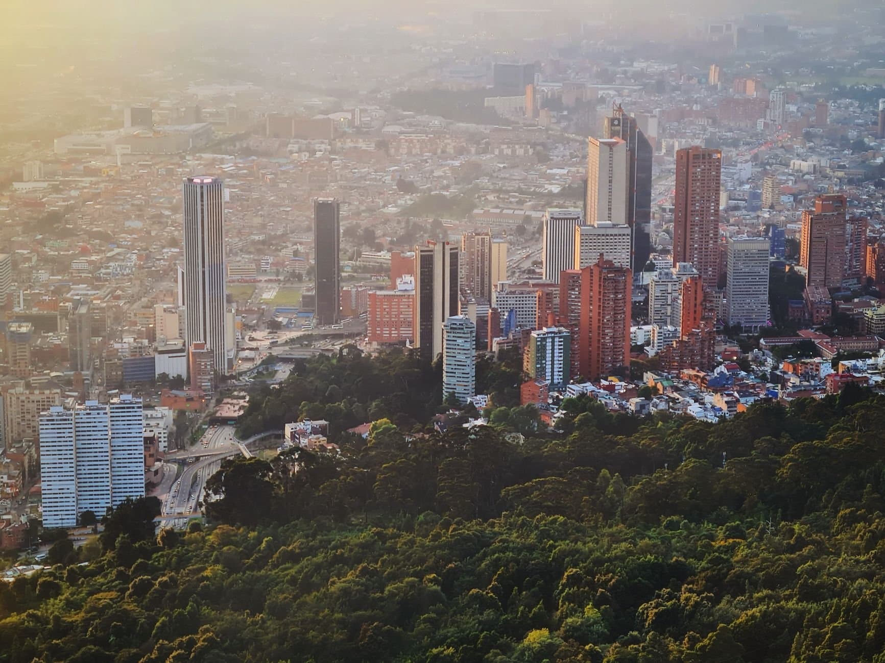 Aerial view of Bogotá showcasing its forested outskirts and iconic skyscrapers at daytime.