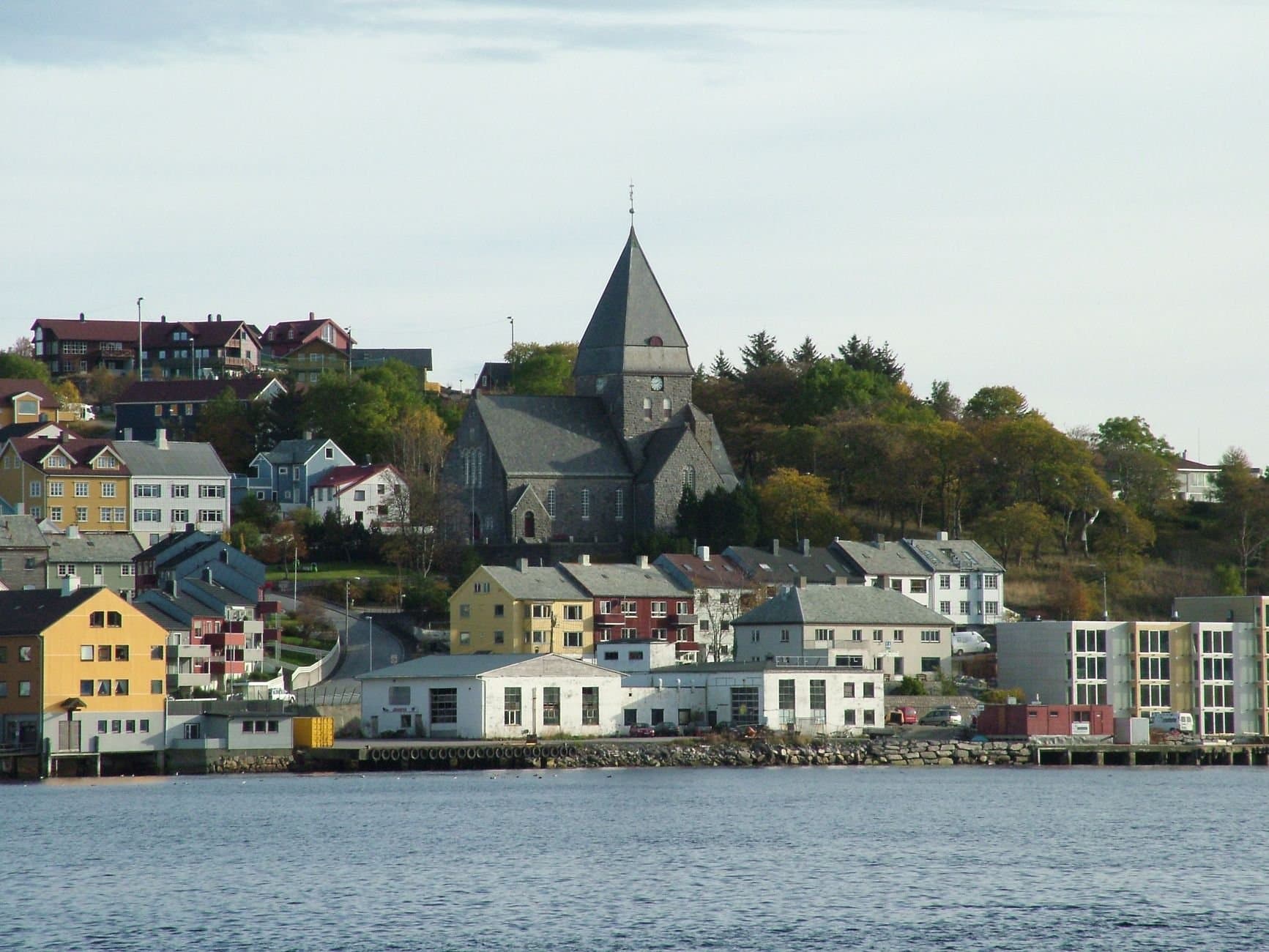 Picturesque view of a coastal town with a prominent stone church and colorful buildings.