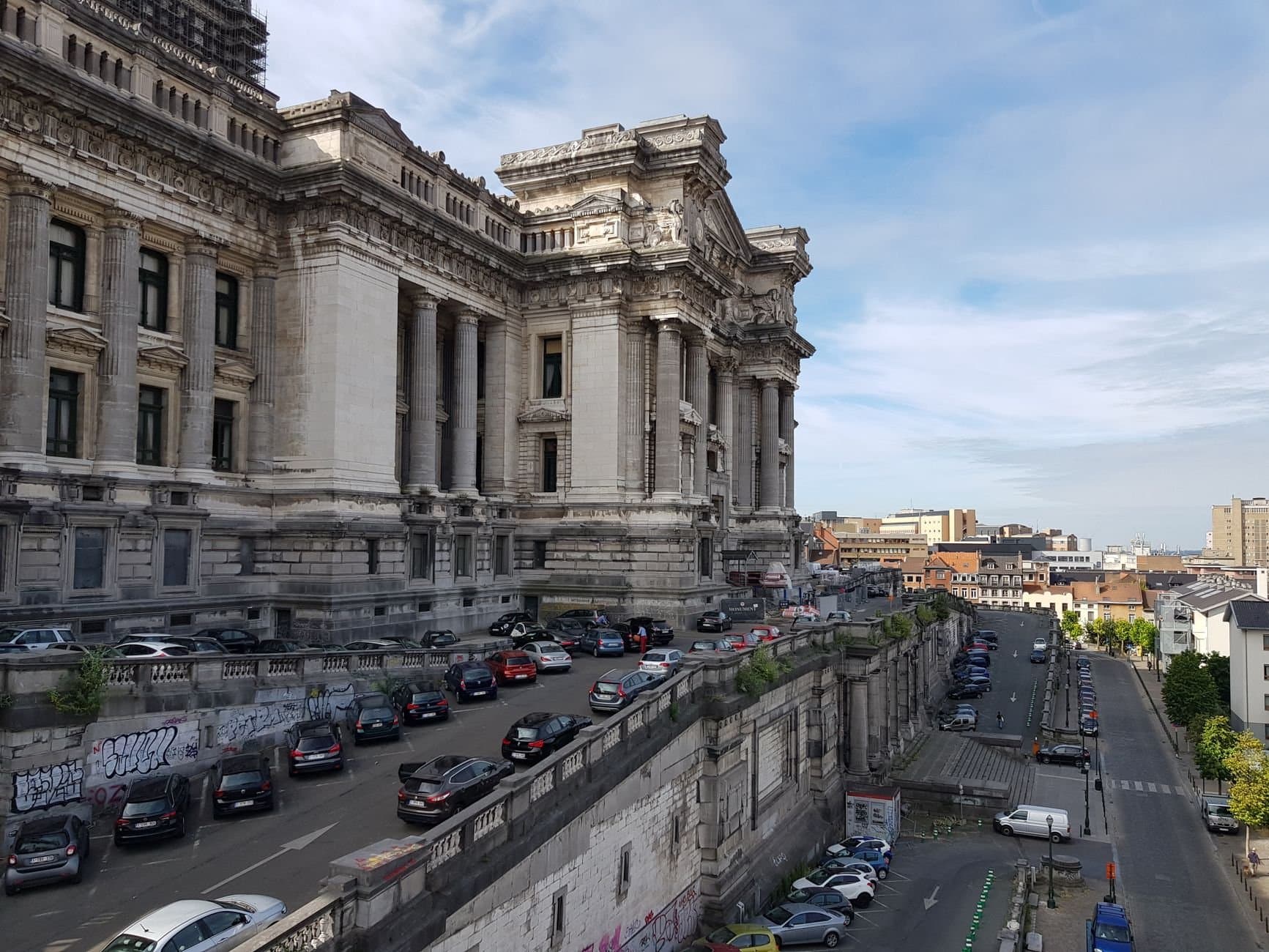 View of Brussels' iconic Palais de Justice with parked cars and urban landscape.