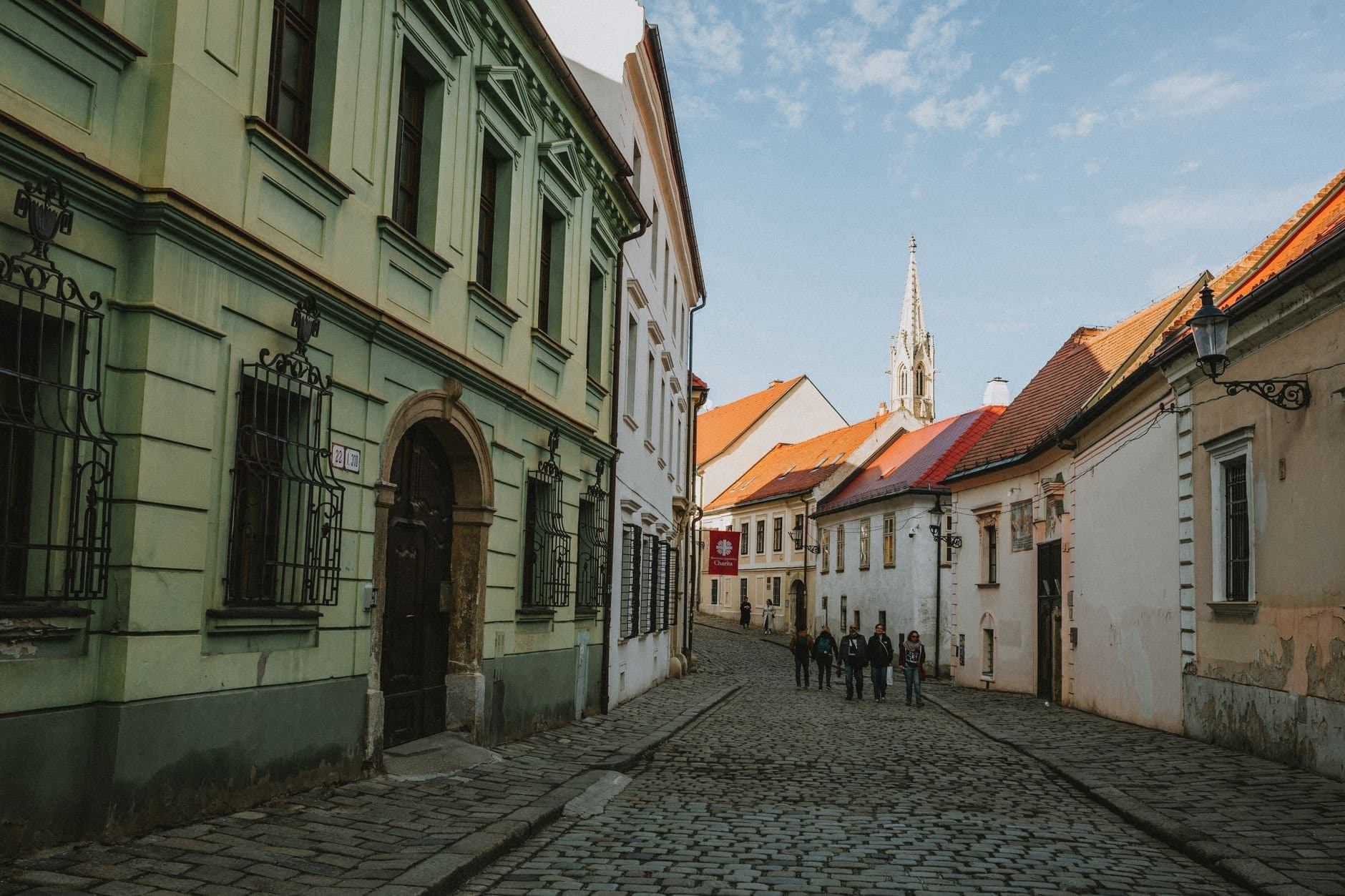 Charming cobblestone street in Old Town Bratislava with historic architecture and pedestrians.