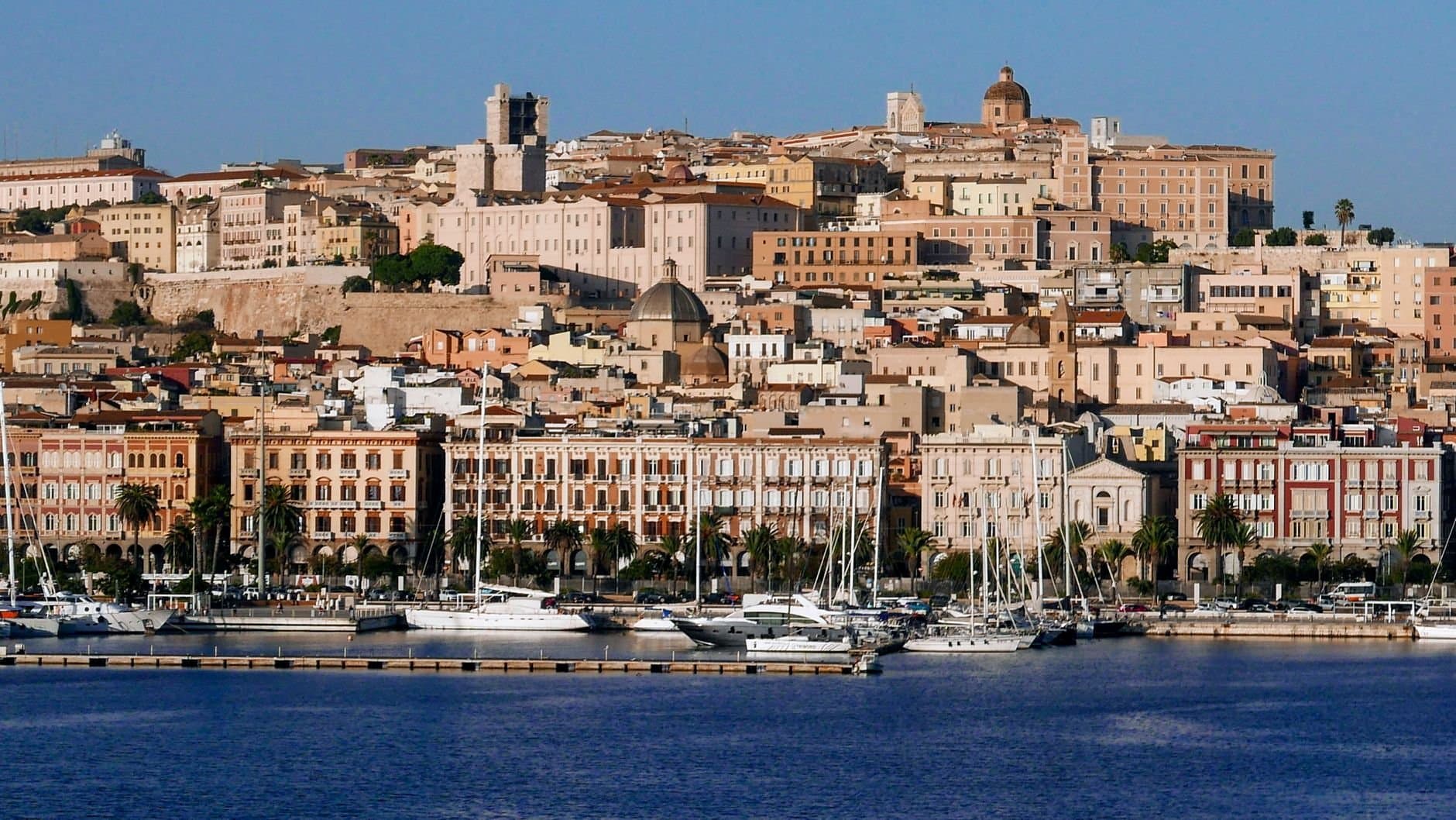 Discover Cagliari's vibrant waterfront, showcasing stunning architecture bathed in sunlight.