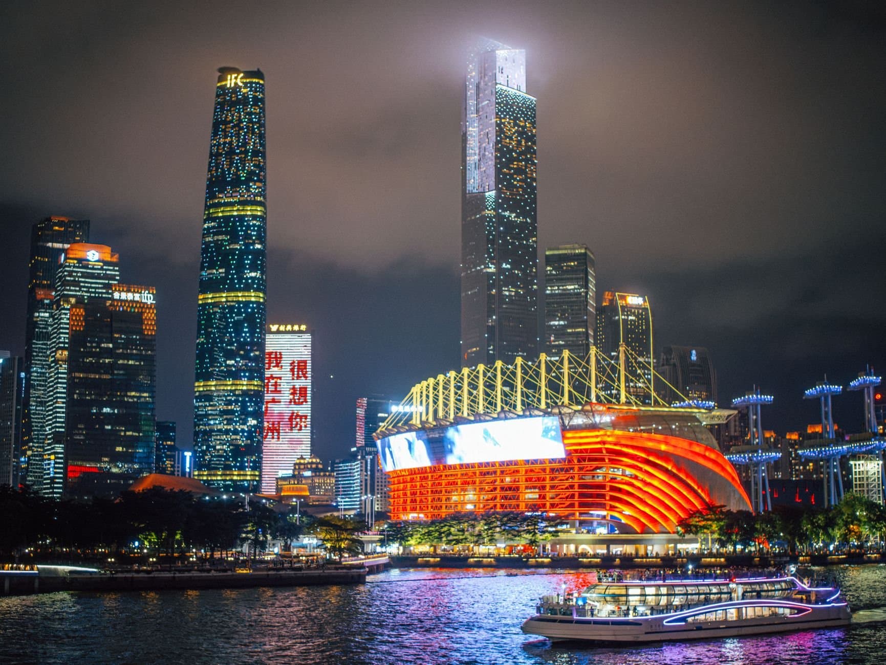 Stunning nighttime view of Guangzhou skyline with illuminated skyscrapers and riverfront.