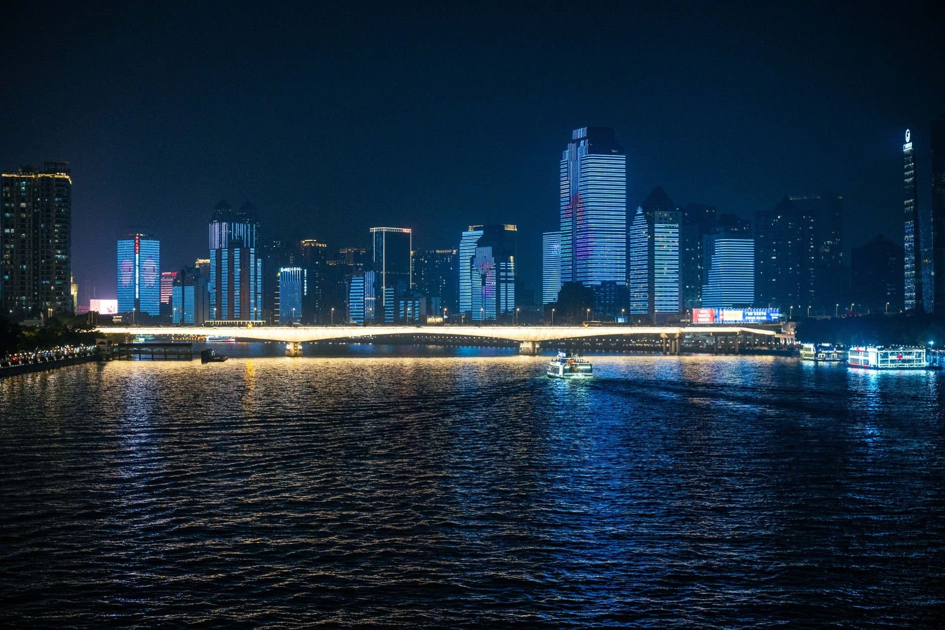 Stunning nighttime cityscape featuring illuminated skyscrapers and a reflective river view.