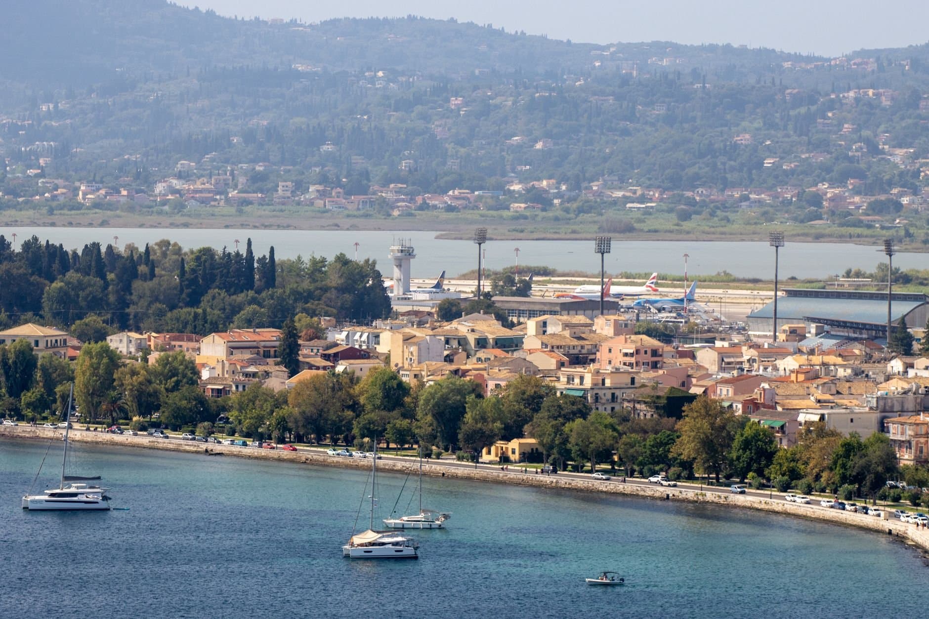 Stunning aerial view of Corfu's coastline with yachts and lush greenery, capturing Greek island charm.