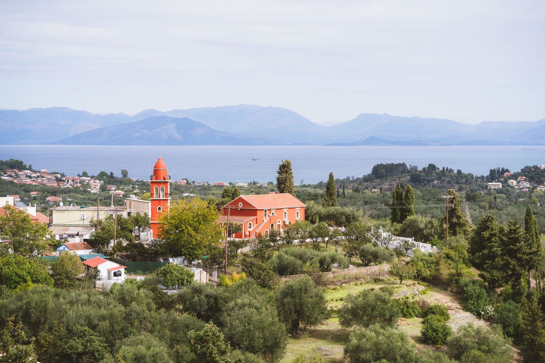 Discover a serene church landscape in Corfu, Greece, overlooking the sea and lush greenery.