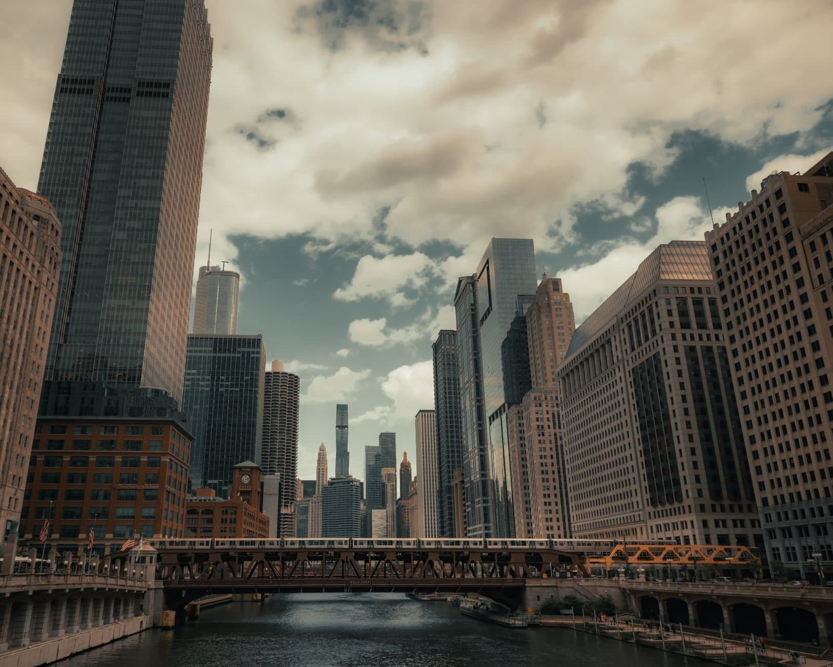 A stunning view of Chicago's skyline and river with prominent skyscrapers and bridges on a cloudy day.